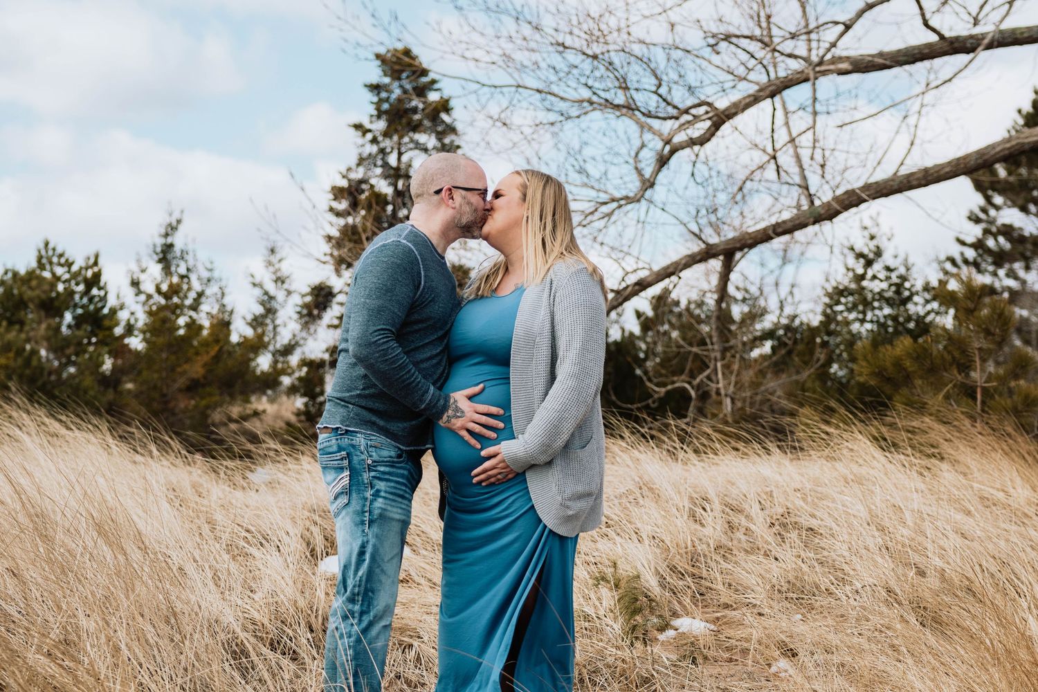 A couple embracing in a field of tall golden grass on a bright autumn day.