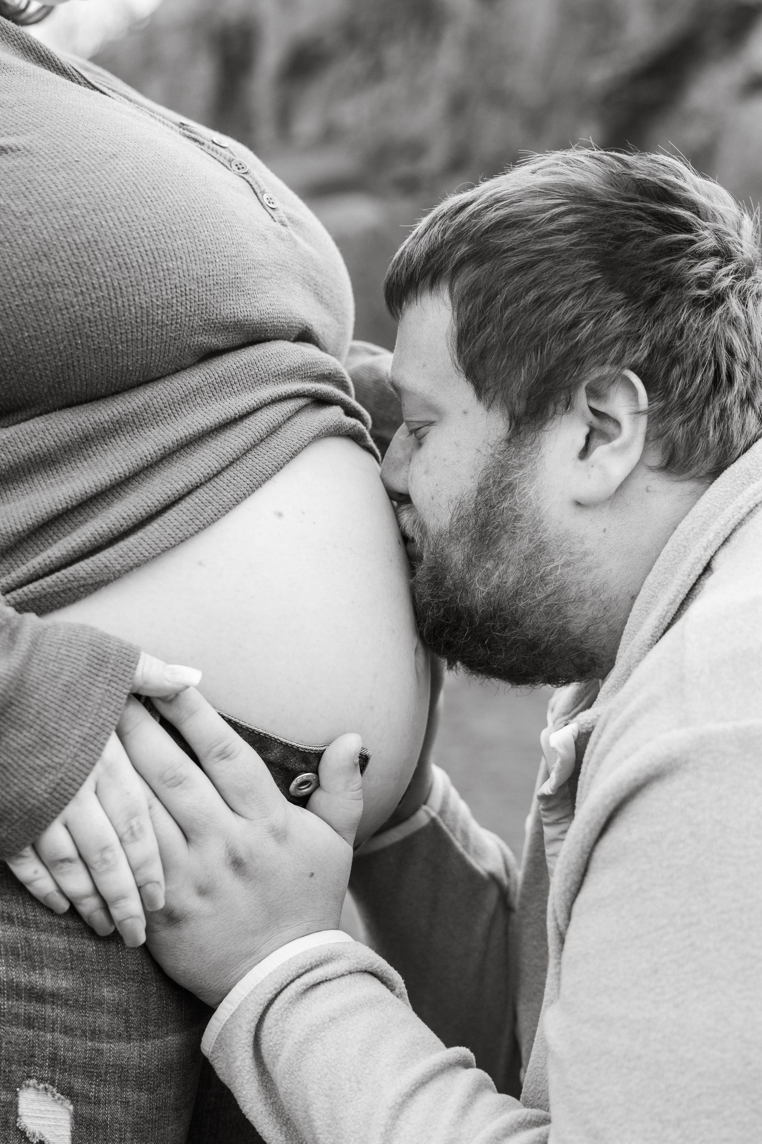 An intimate black and white moment of a gentle kiss on a pregnant belly. Black Sand beach Silver Bay MN