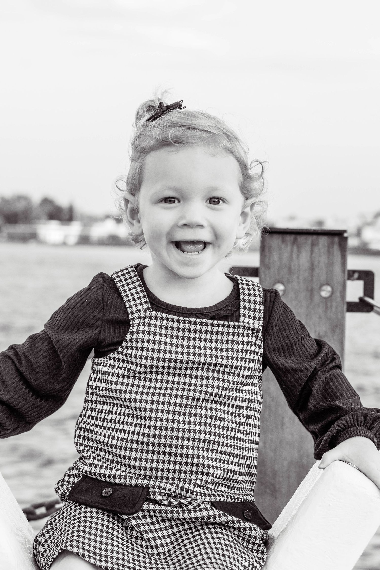 Black and white collage of a young child wearing a houndstooth dress and black top while playing outdoors.