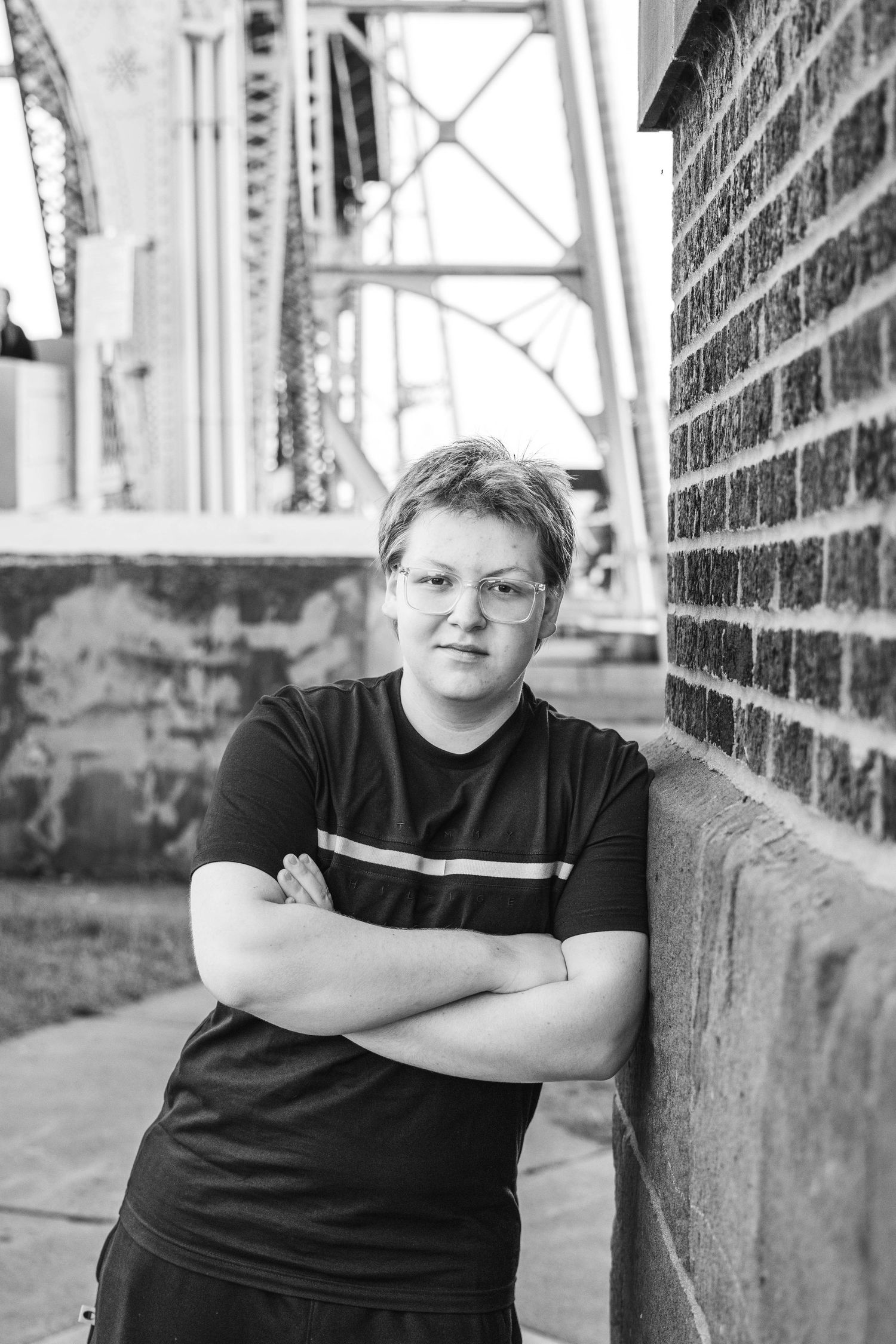 Black and white portrait series showing person in dark shirt leaning against brick wall in various poses.