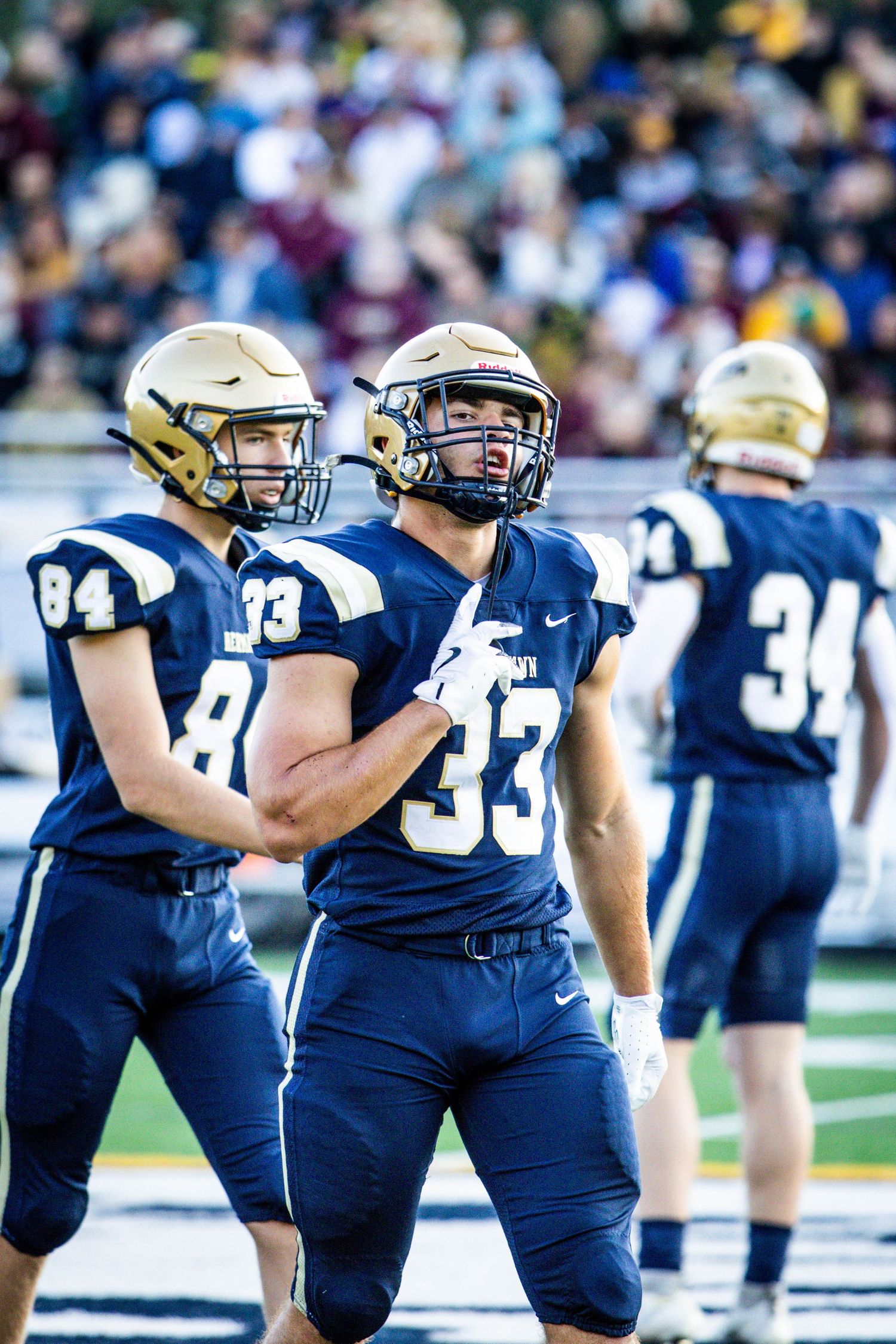 A row of Navy football players lined up in blue uniforms stretches across the field during practice or warmup drills.