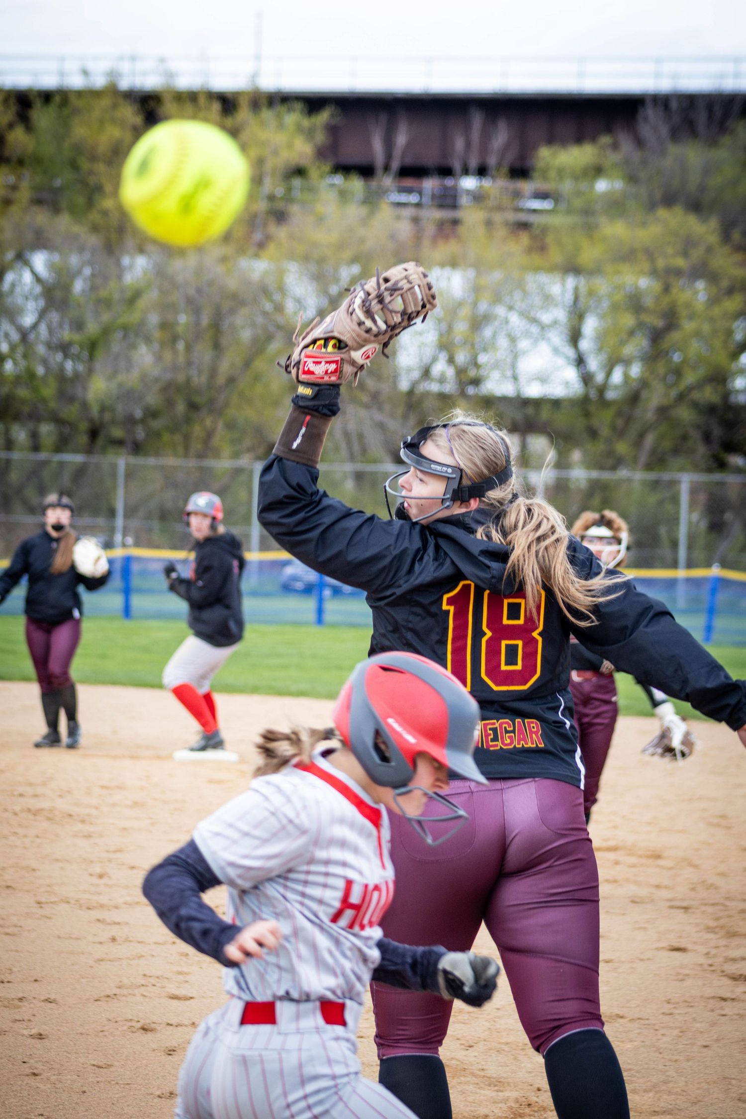Sequence of softball action shots showing players fielding a high pop fly ball during a game.
