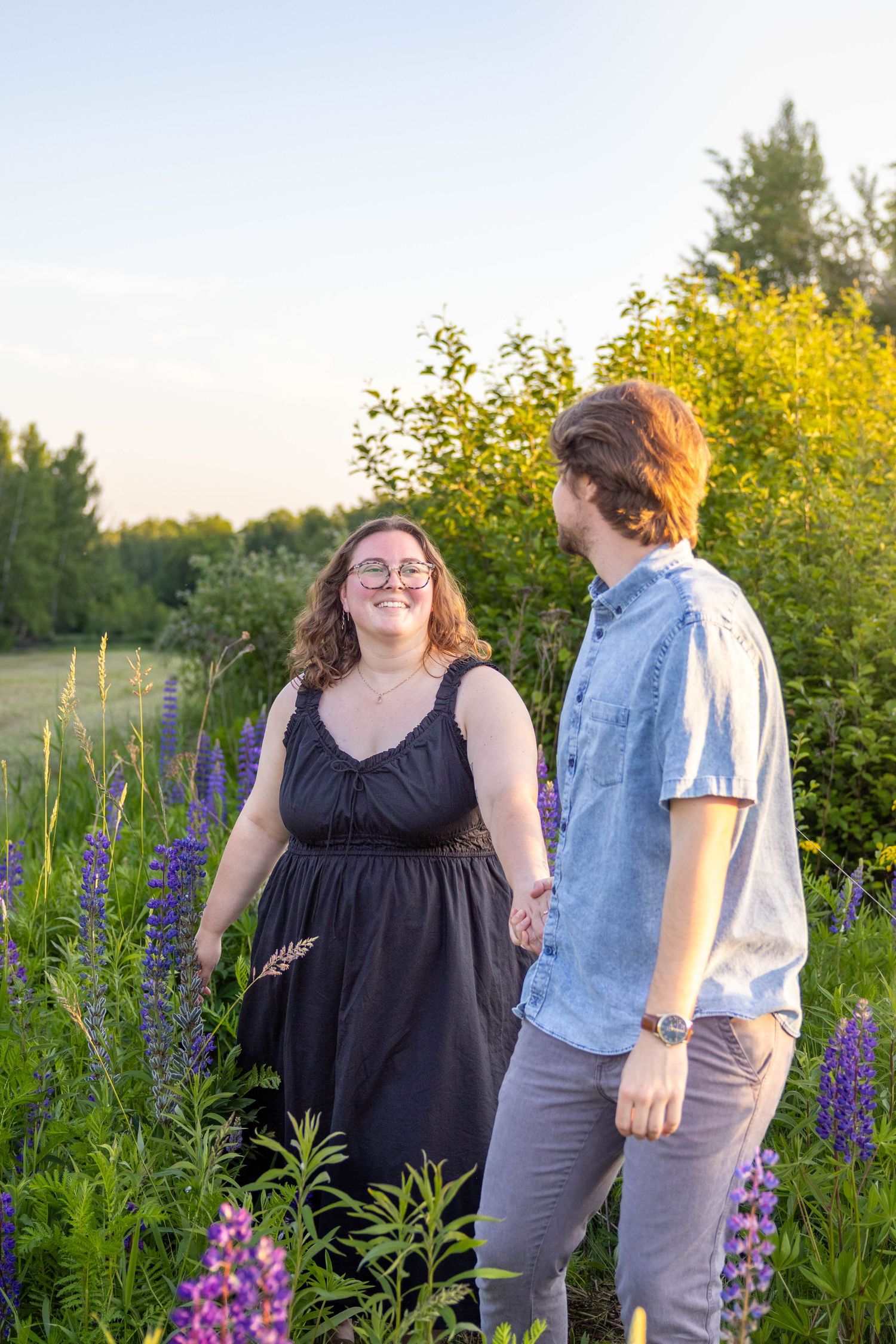 A couple shares a joyful moment together in a field of purple lupines and yellow wildflowers at sunset.