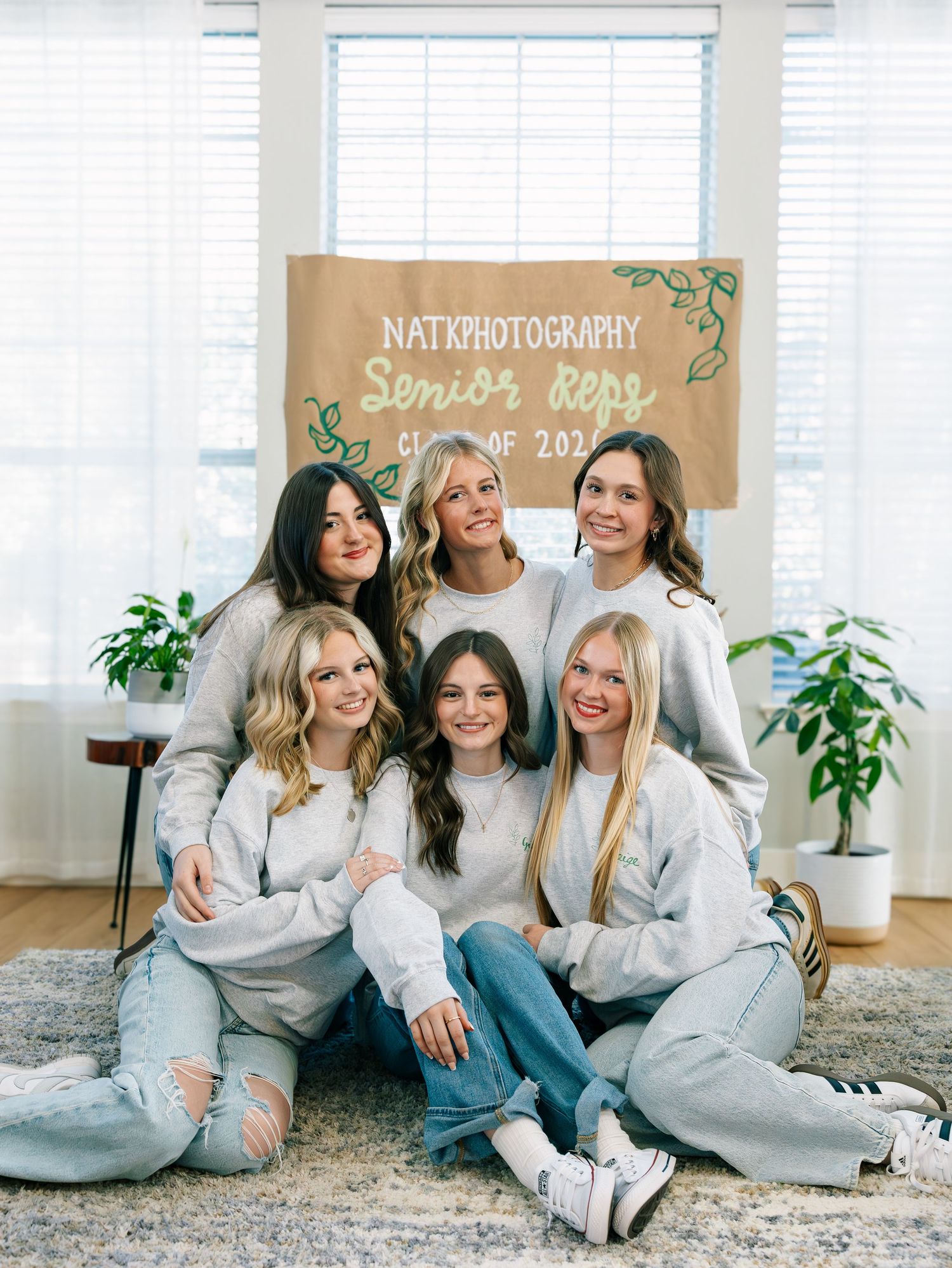 Seven young women in matching gray sweatshirts pose together for NATK Photography Senior Reps Class of 2023 group photo.