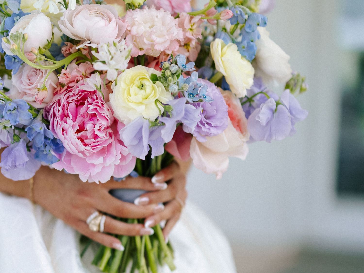 Bride holding a lush pastel wedding bouquet with pink peonies, lavender sweet peas, and blue hydrangeas.