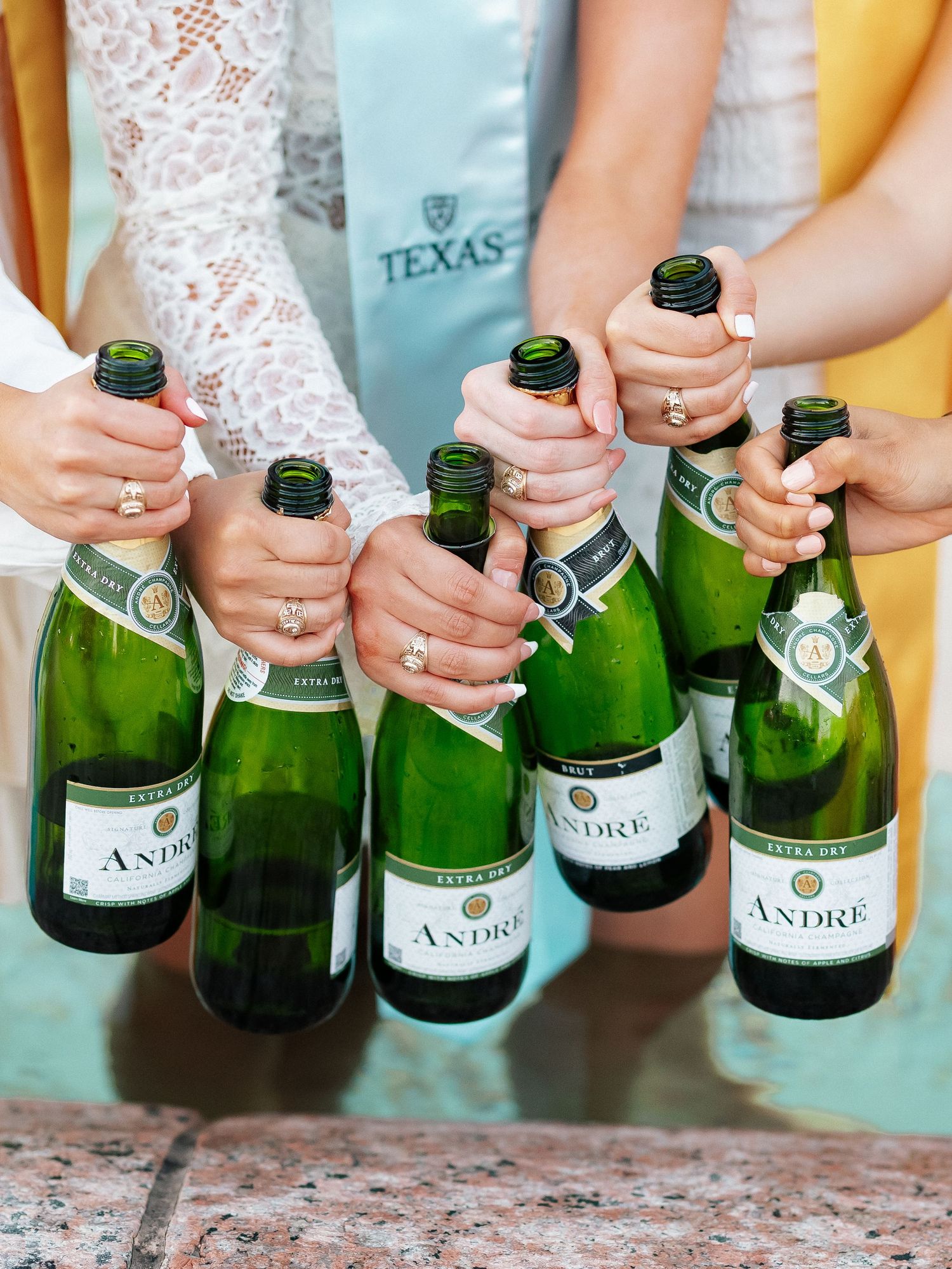 Group of women holding André Extra Dry sparkling wine bottles together at a Texas celebration event.