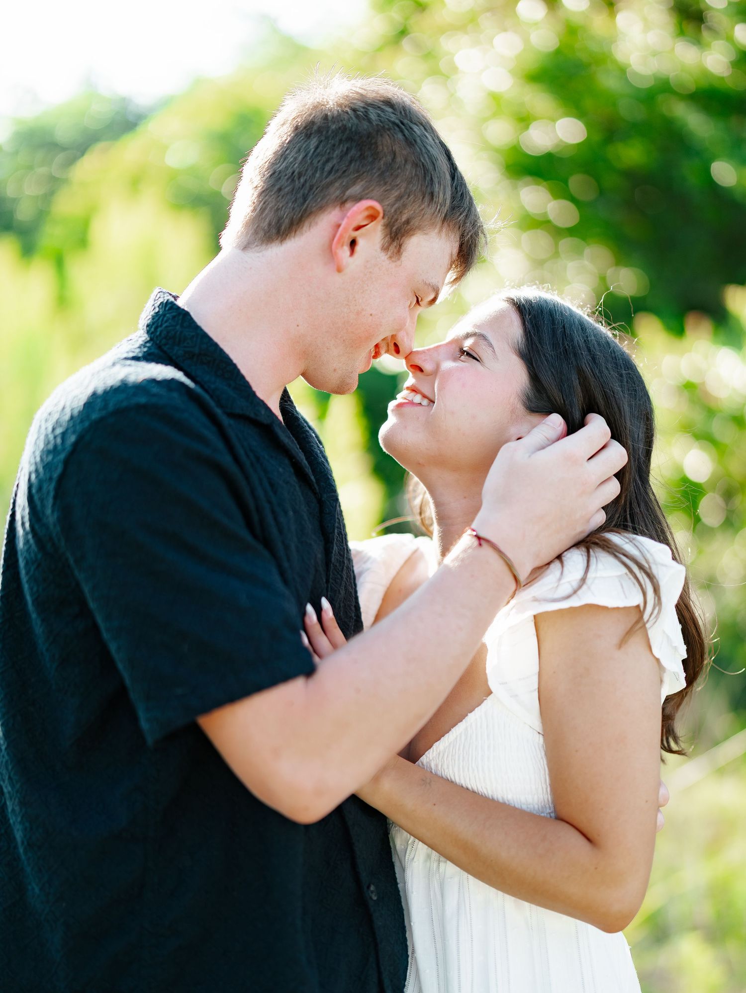 Romantic couple sharing a tender moment about to kiss in a sun-drenched outdoor setting.