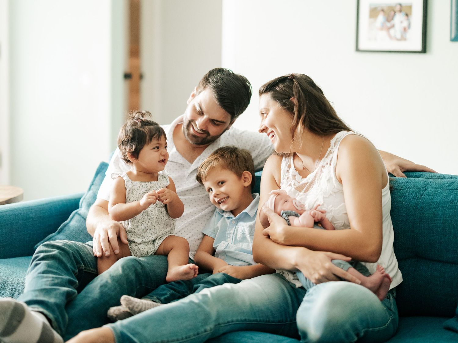 Joyful family of five sharing a warm moment together on a blue couch indoors.