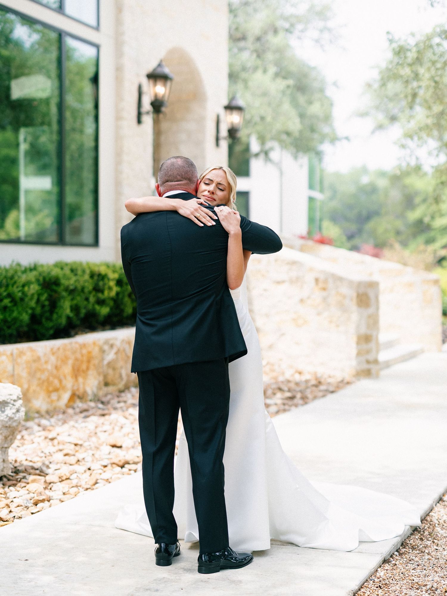 Bride and groom share tender first look embrace outside stone wedding venue.