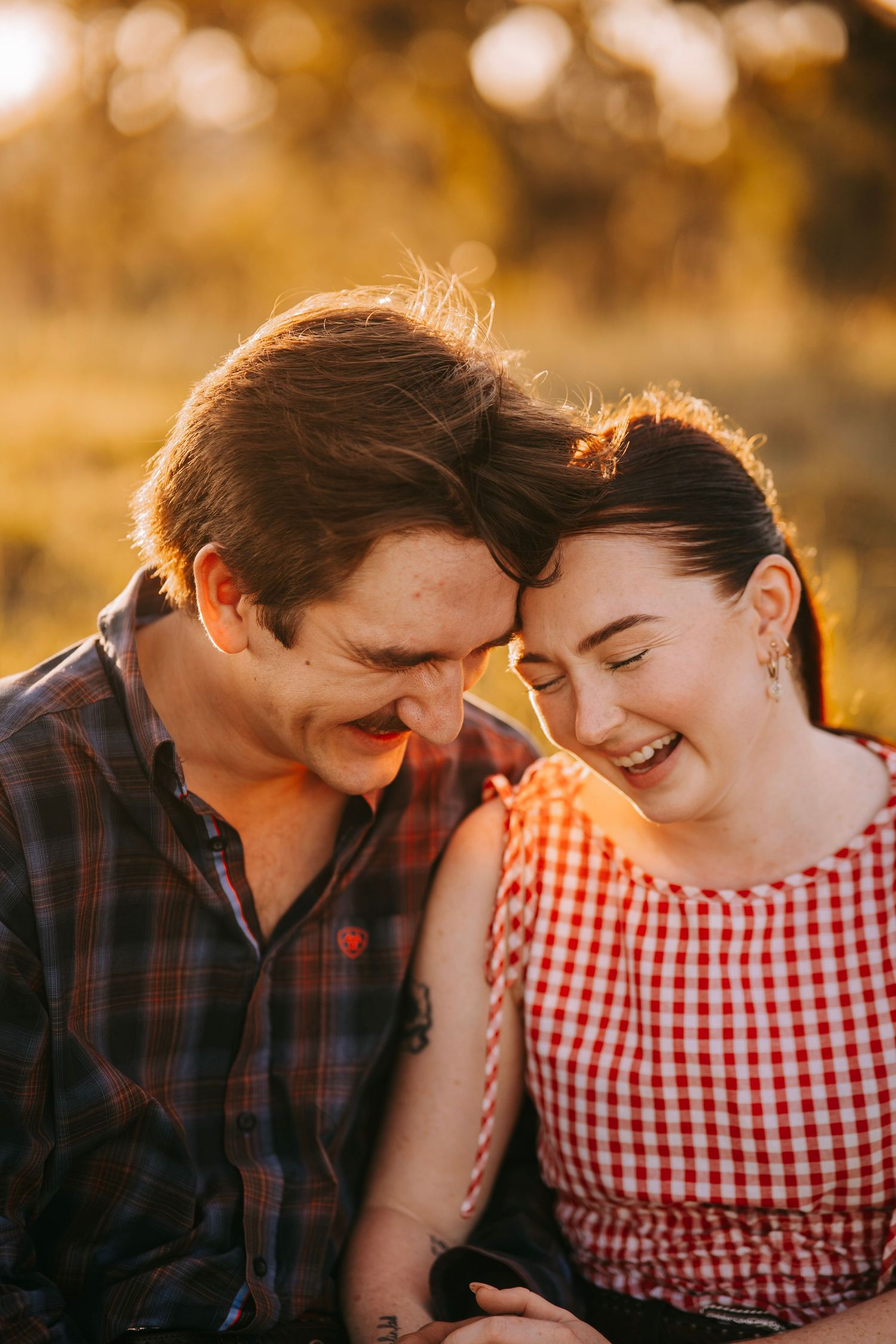 A happy couple laughing together outdoors in warm golden sunset light.