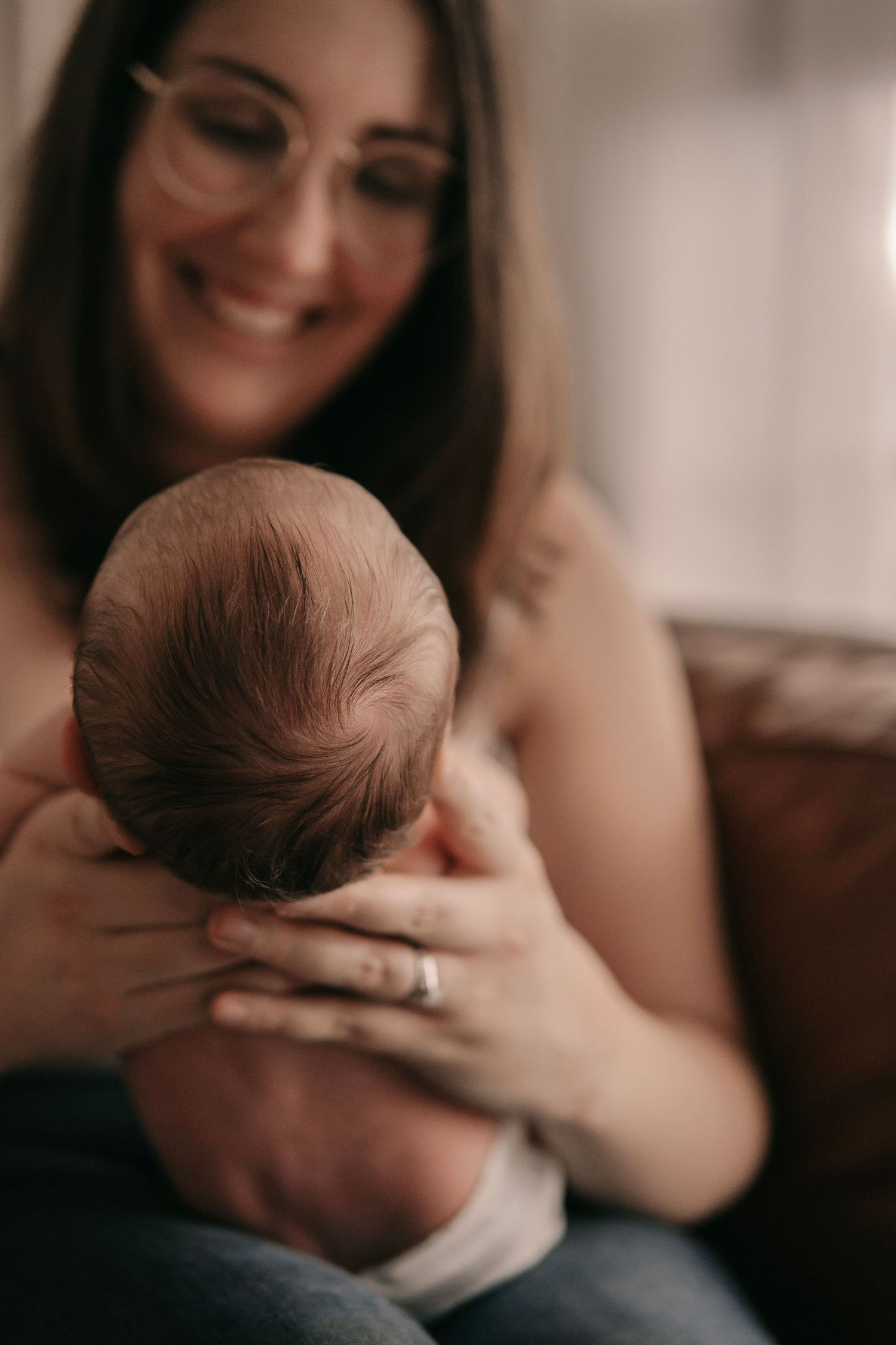 Smiling mother with glasses lovingly cradling her newborn baby.