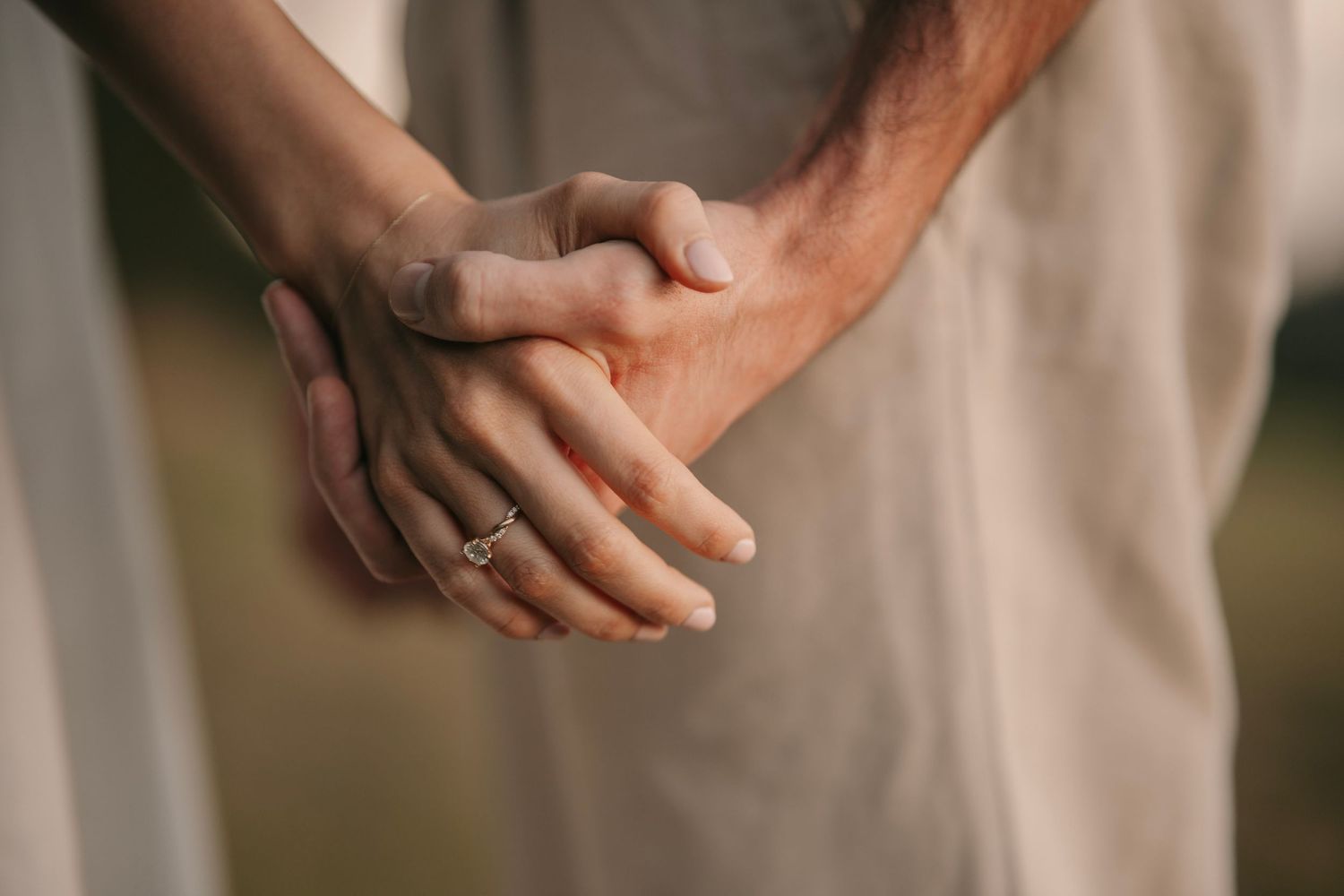 Close-up of a couple holding hands tenderly, woman wearing a delicate silver ring.