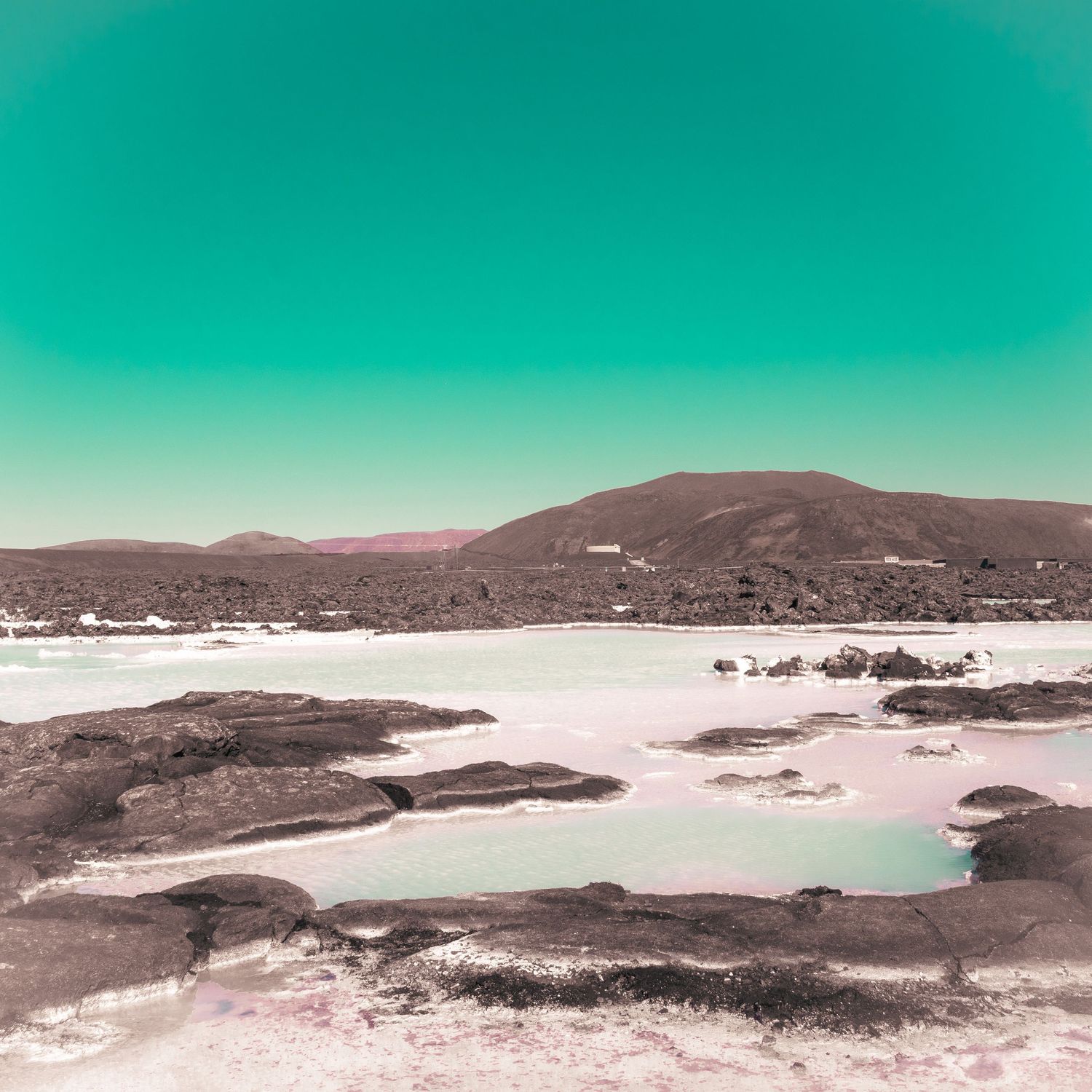 Desert-like terrain with surreal pink tones under a bold turquoise sky
