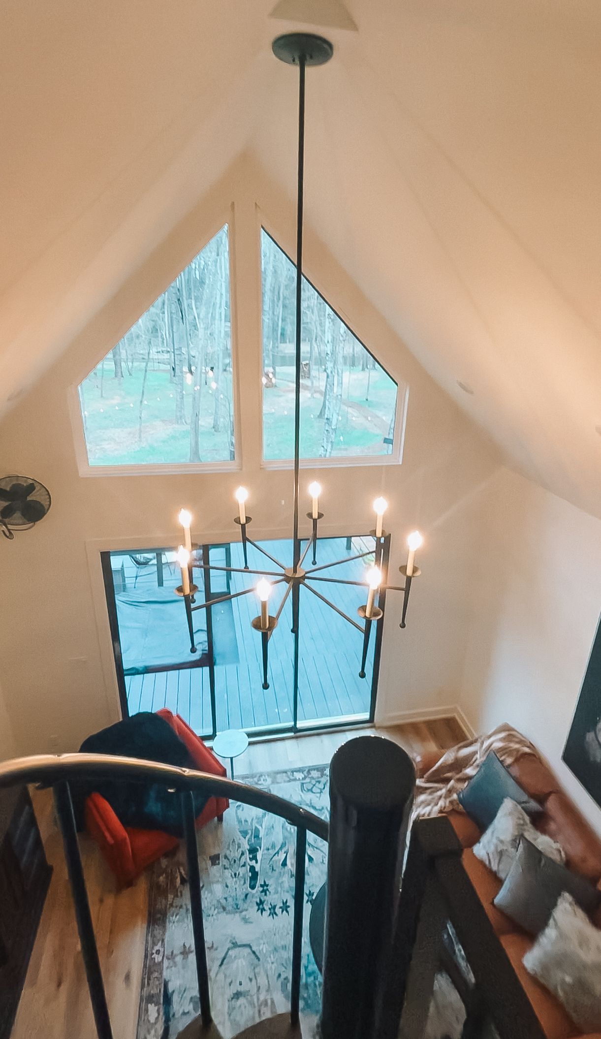 Cozy loft interior with chandelier, triangular window, and eclectic furniture setup