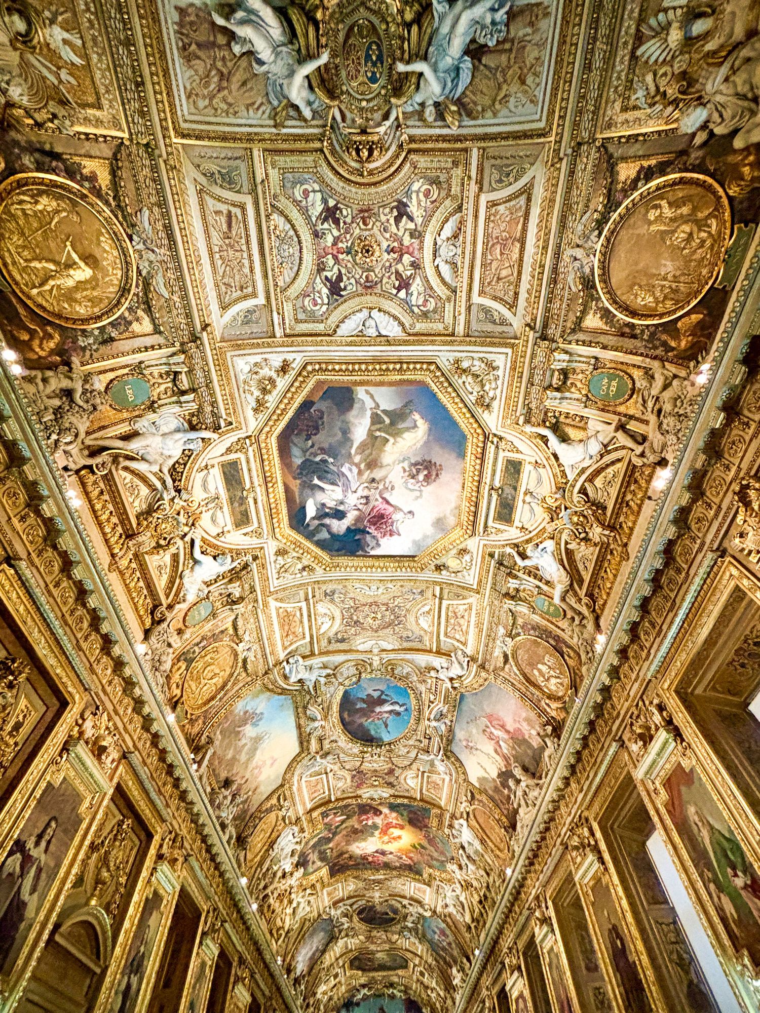 Ornate ceiling with golden details and Renaissance-style paintings in a historic Paris museum