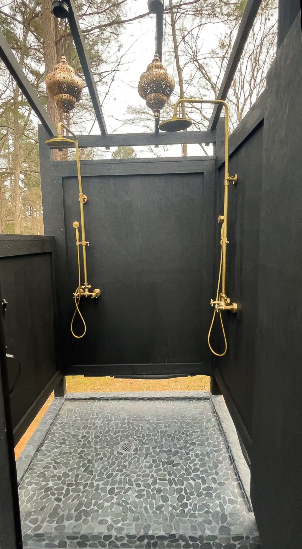 Outdoor black shower with brass fixtures and Moroccan-style lanterns