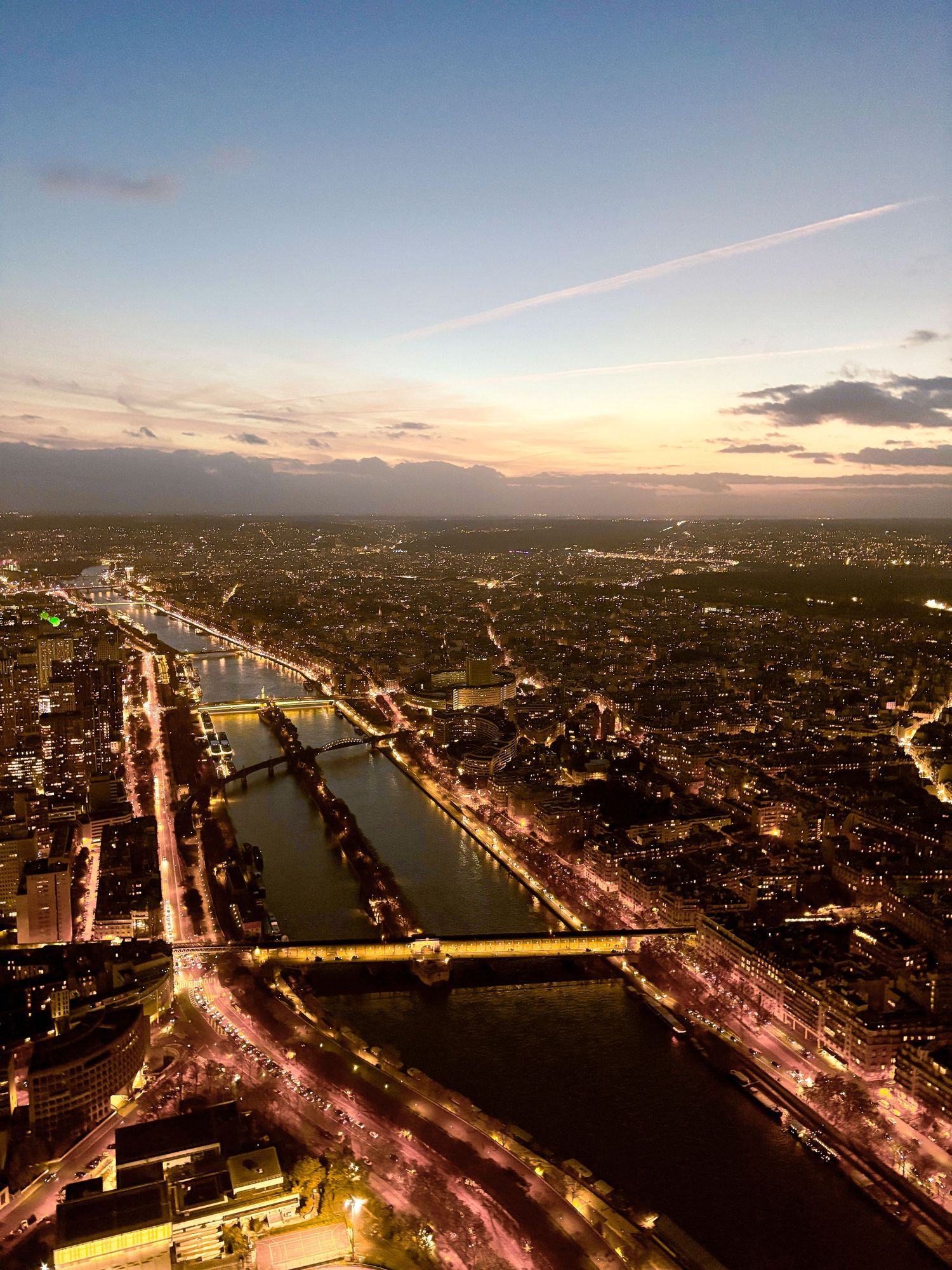 Aerial view of city at sunset with glowing streetlights and a river running through downtown