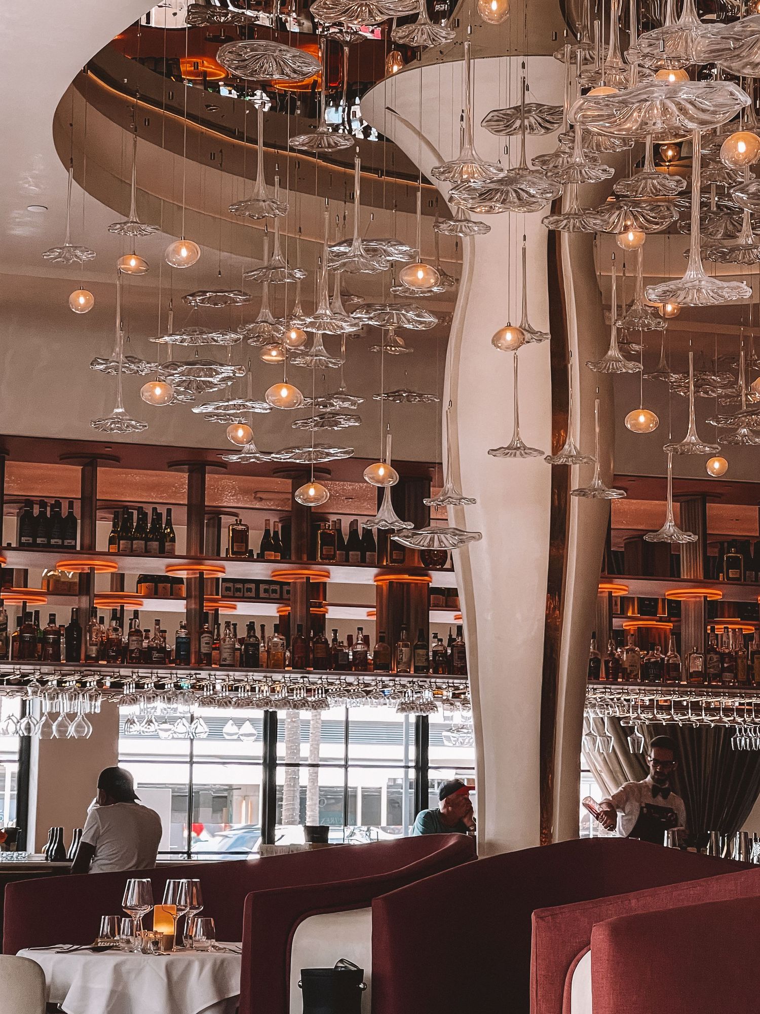 Modern restaurant with high ceilings, chandeliers, and warm ambient lighting