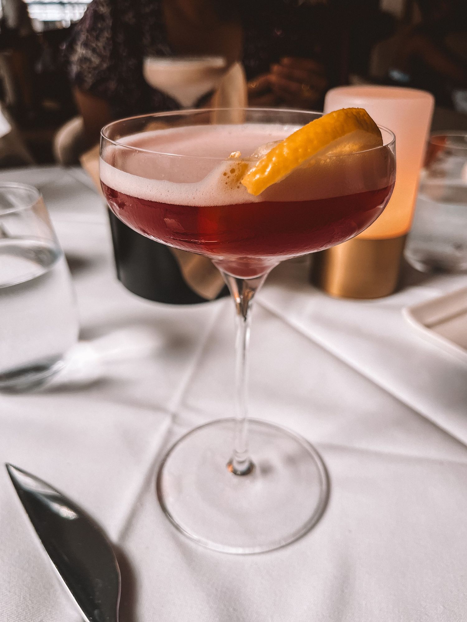 Elegant cocktail garnished with citrus peel served on a white table setting