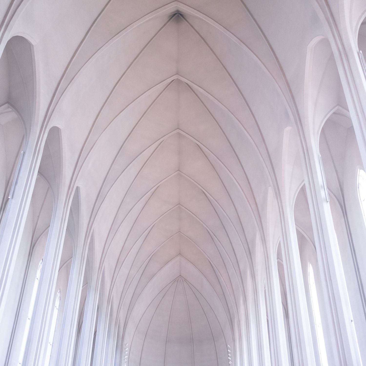 Arched white ceiling of a minimalist cathedral with soft light and repeating curves