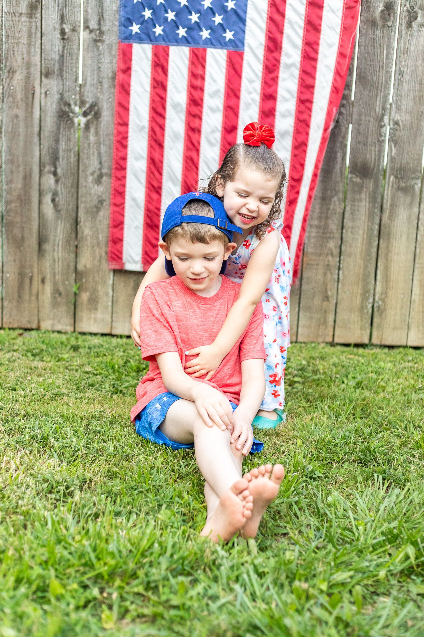 Playful summer scene with children laughing in front of American flag decoration.