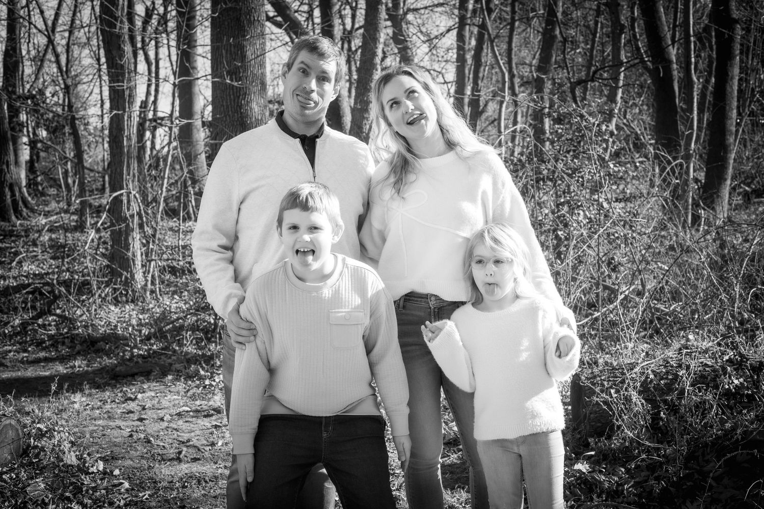 Black and white family portrait in natural wooded setting.