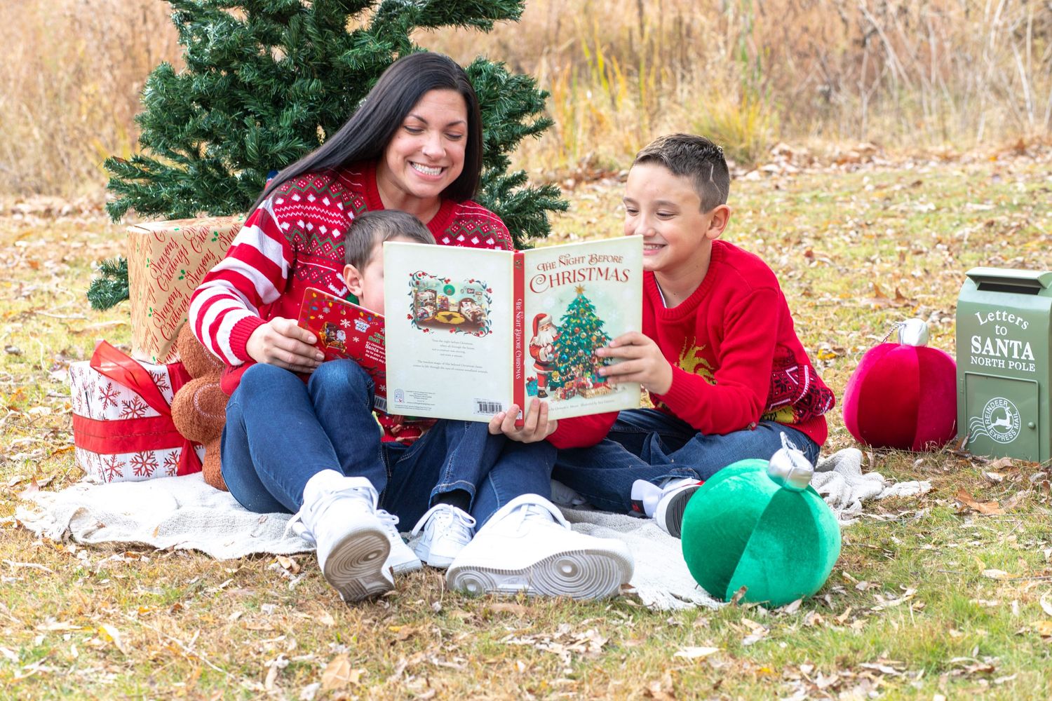 Family reading Christmas stories together on blanket outdoors.