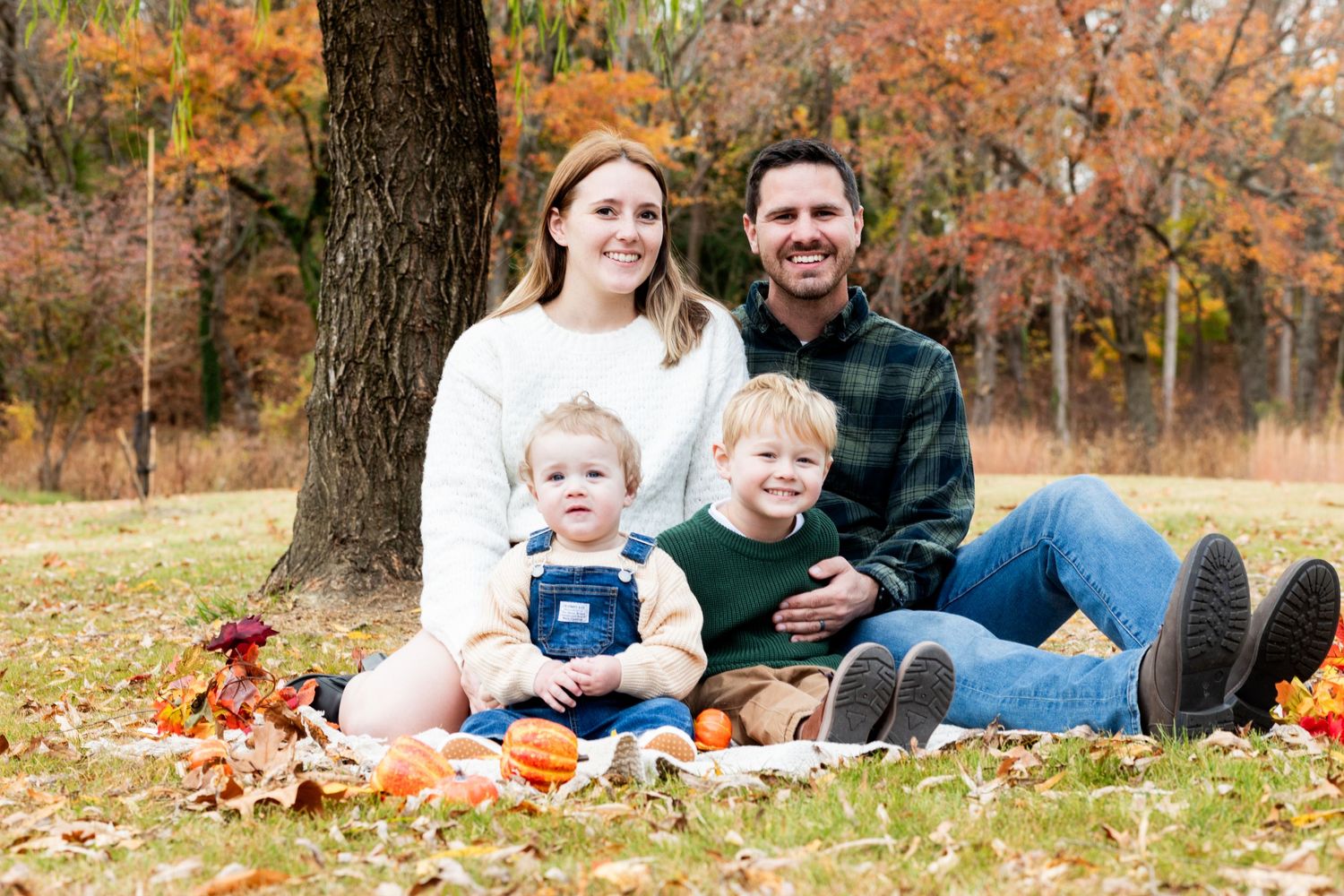 Family photo session in autumn park with fallen leaves and warm colors.