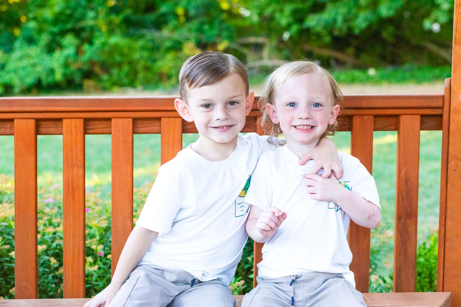 Group photo on wooden deck with bright green foliage and flowers in background.