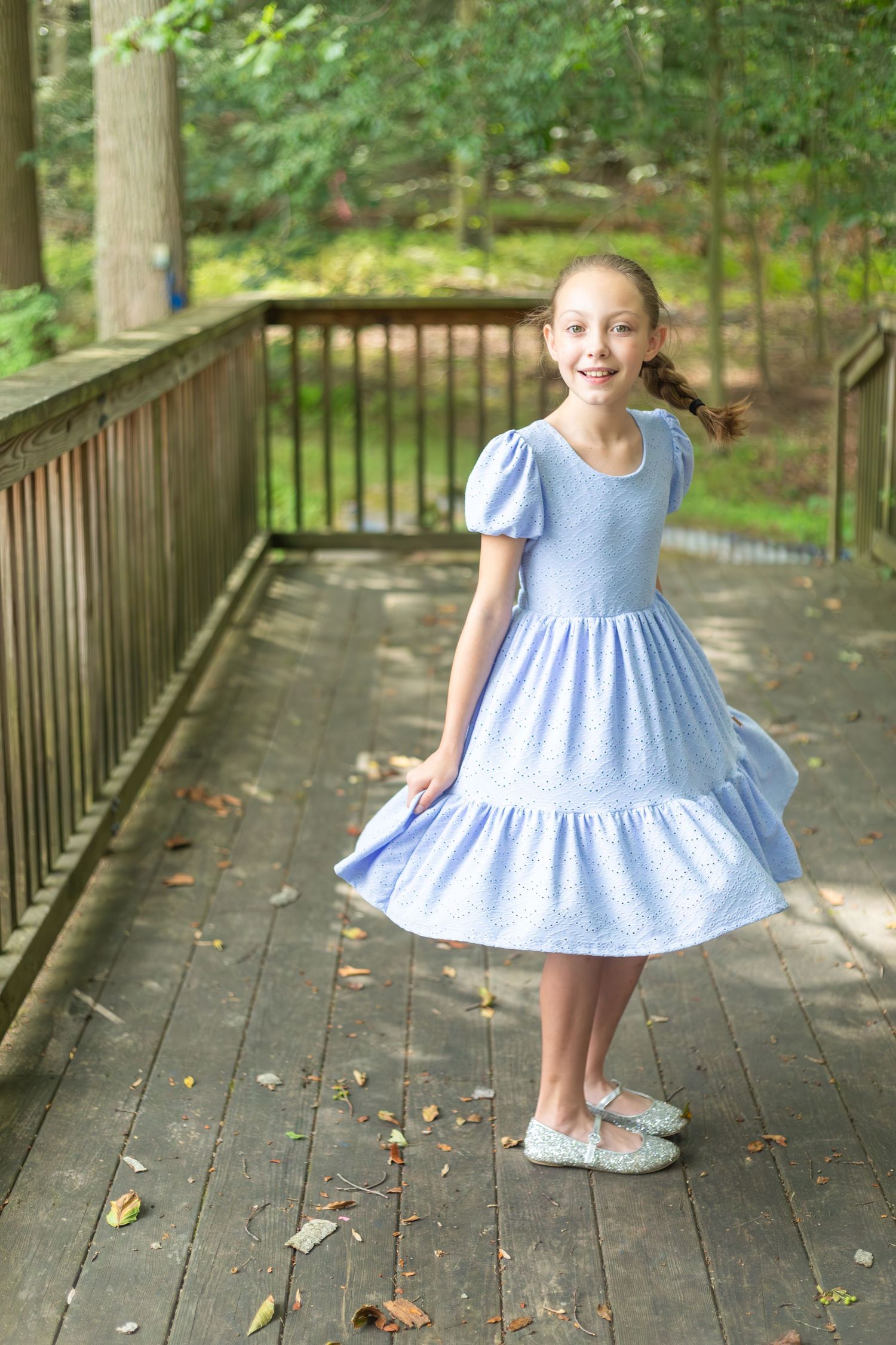 A playful sequence shows someone wearing a light blue dress twirling on a wooden deck surrounded by greenery.
