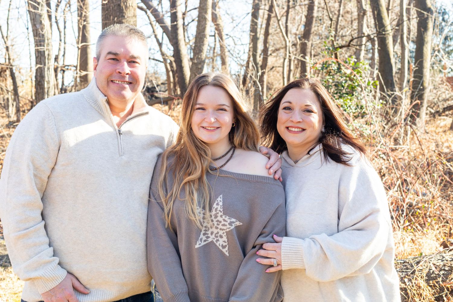 Family portrait session in winter woods with coordinated neutral outfits.