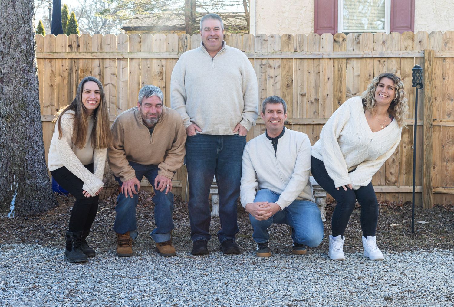 Family photo session outdoors with rustic wooden fence backdrop.