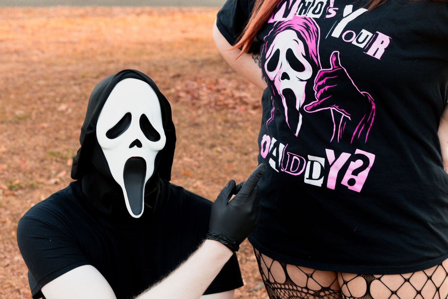 A collection of black t-shirts and face masks featuring white ghost face designs from horror movies arranged in a display.