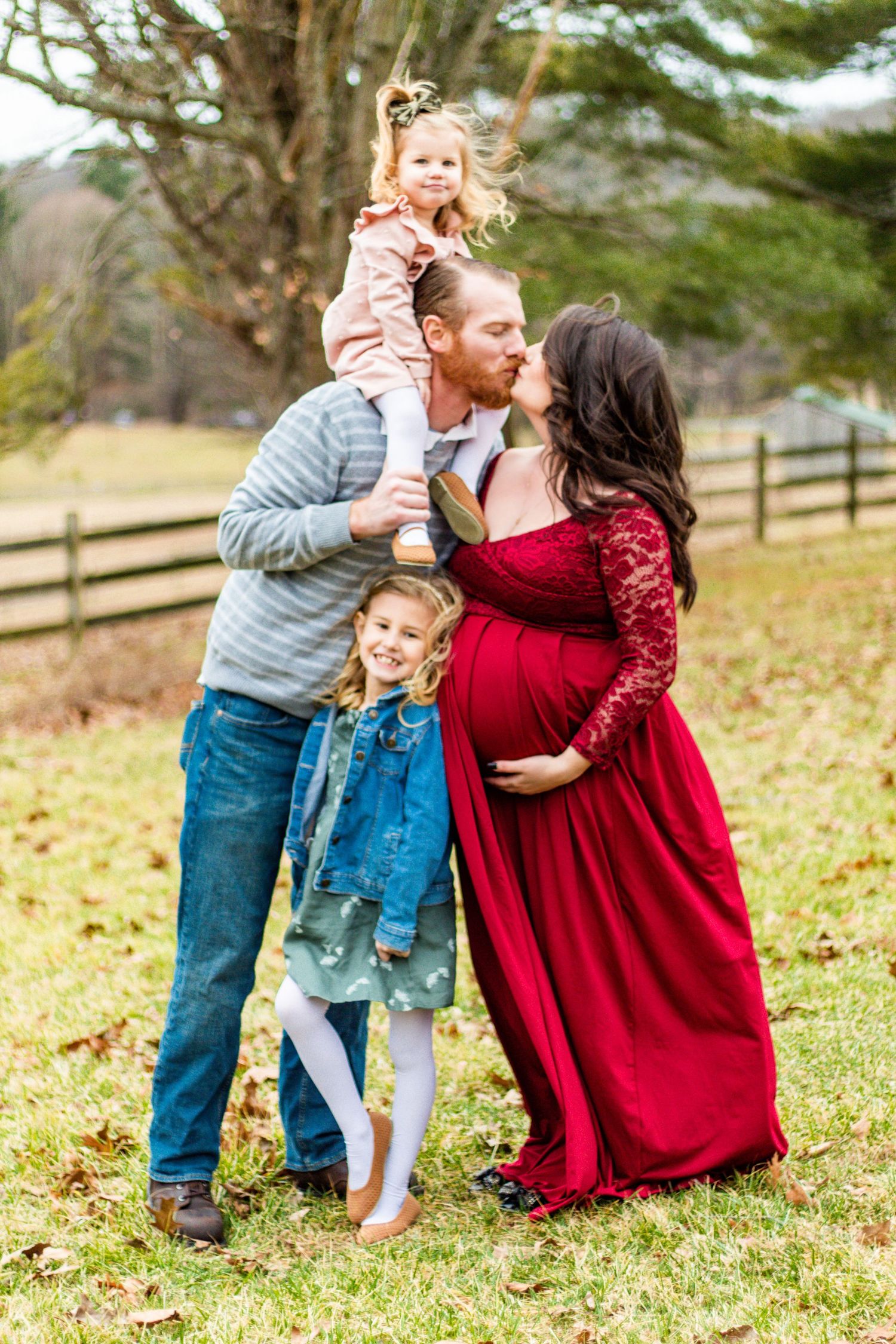Family candid moments in field with red dress and casual outfits.