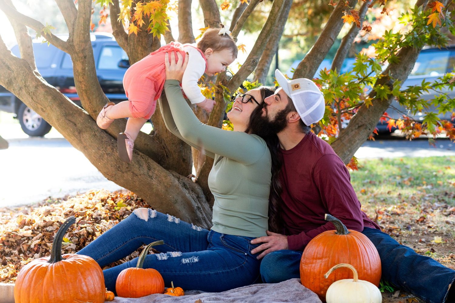 Family relaxing on blanket near pumpkins during fall outdoor session.