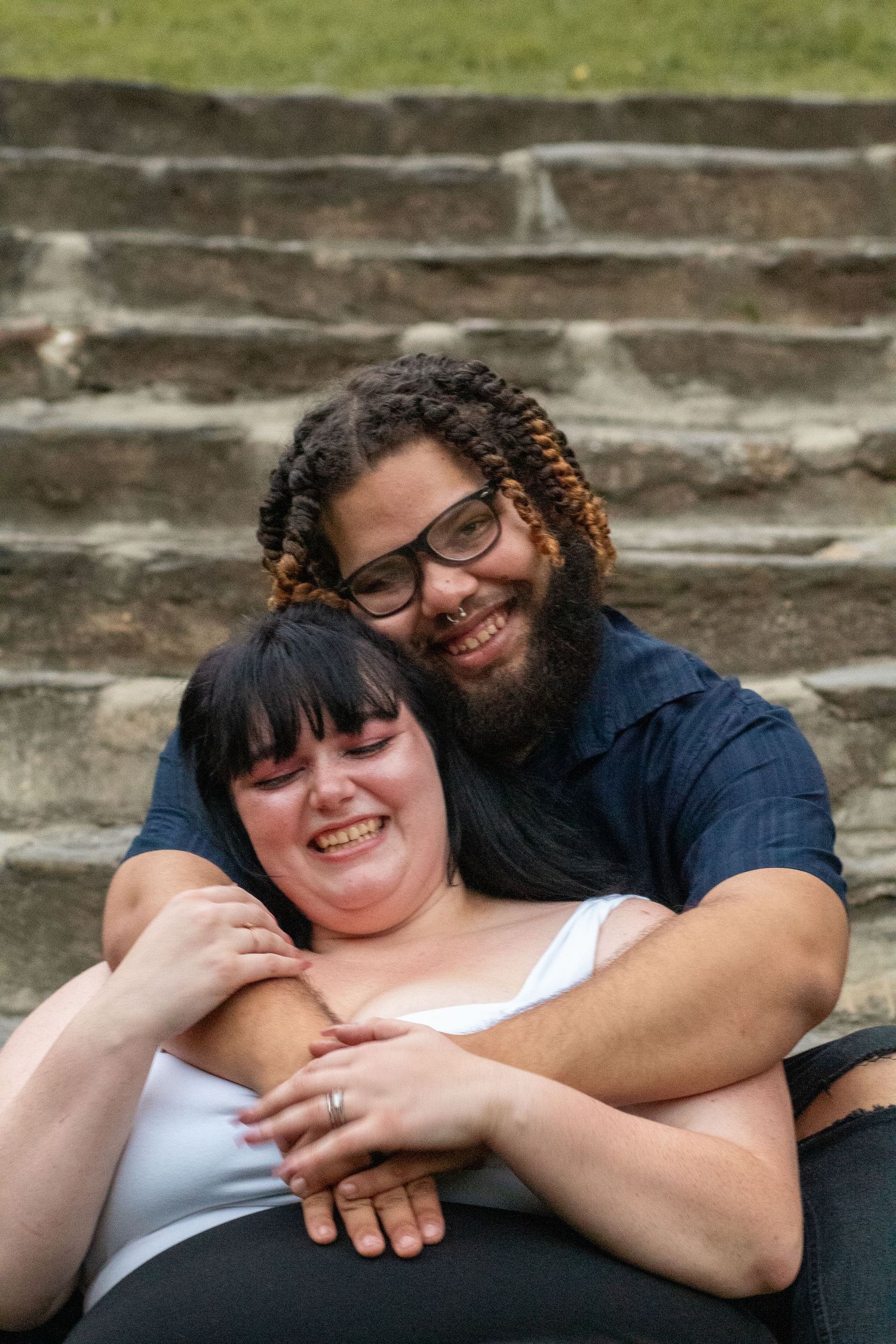 Couple sharing intimate moment while sitting on concrete steps outdoors.