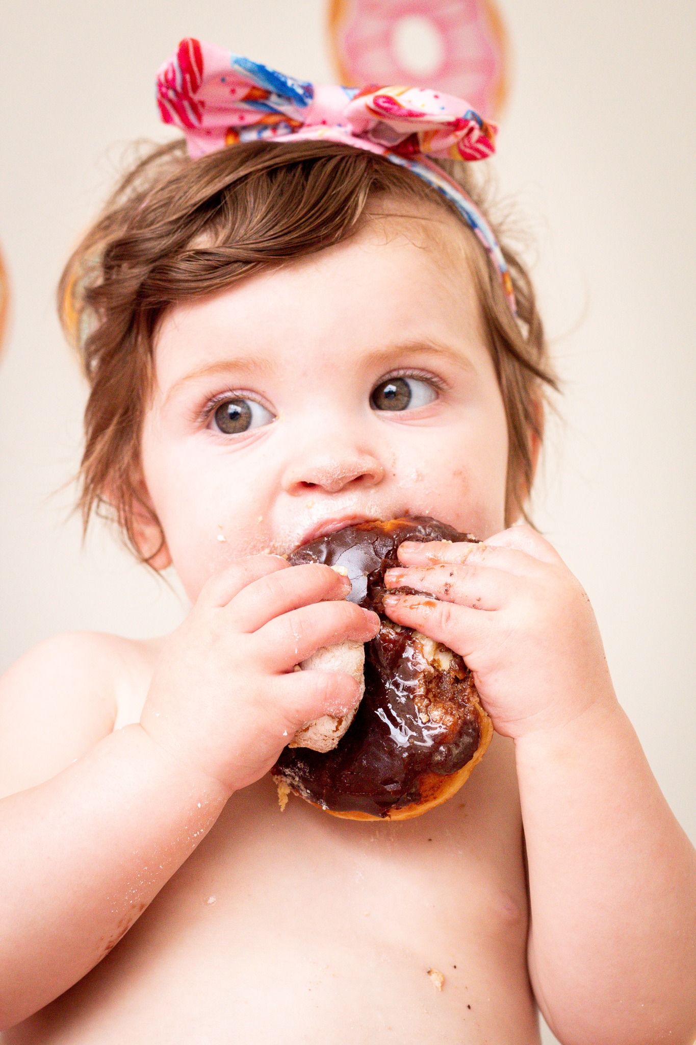Close-up sequence of baby eating chocolate donut with messy hands and face.