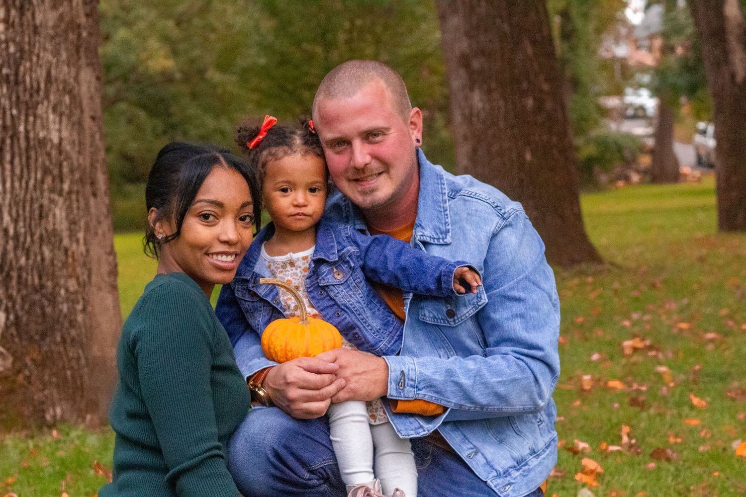 Casual outdoor family portraits in autumn park with pumpkins.