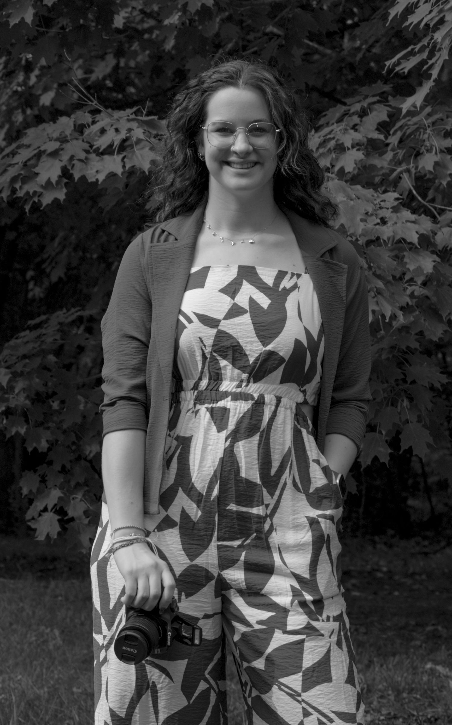 A black and white photo of an experienced photographer, Carley Peterson, holding a camera