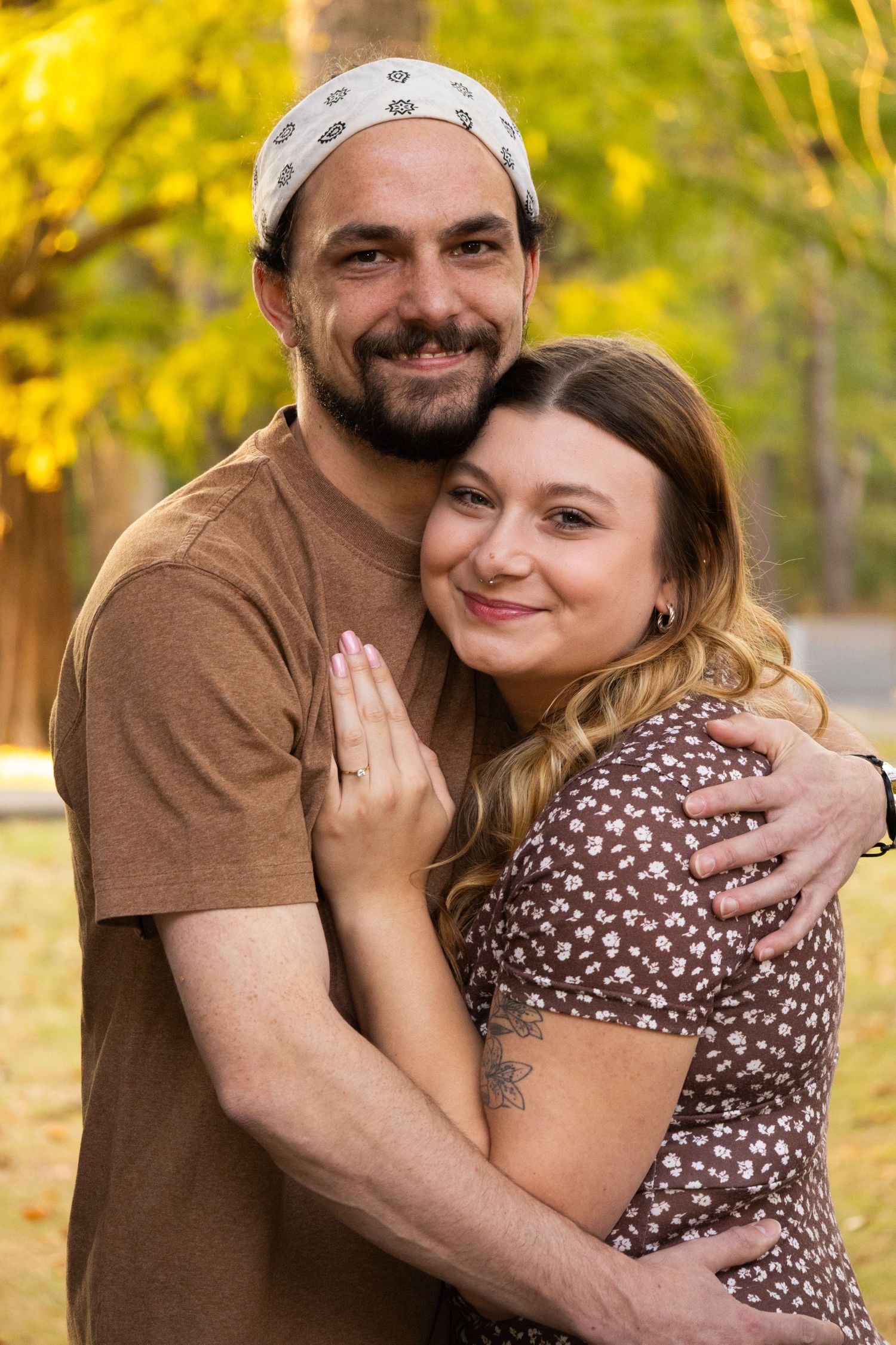 A happily engaged couple's photo in the woods, embracing each other