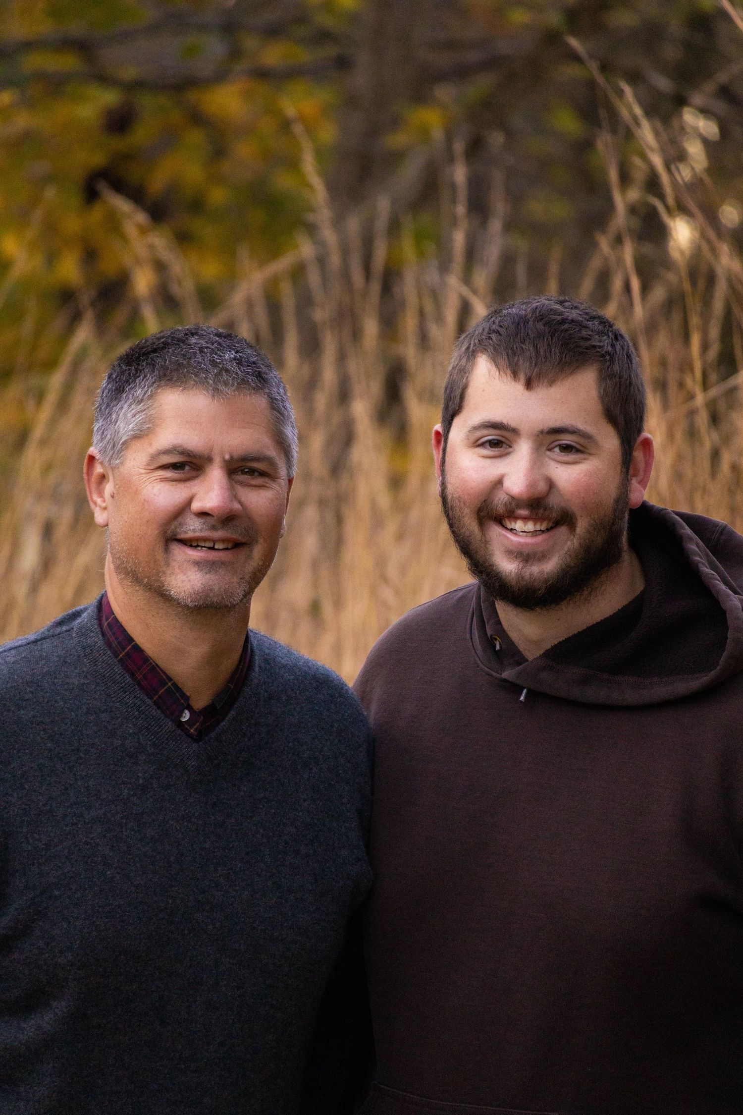 A photo of a father and son smiling together in front of a field