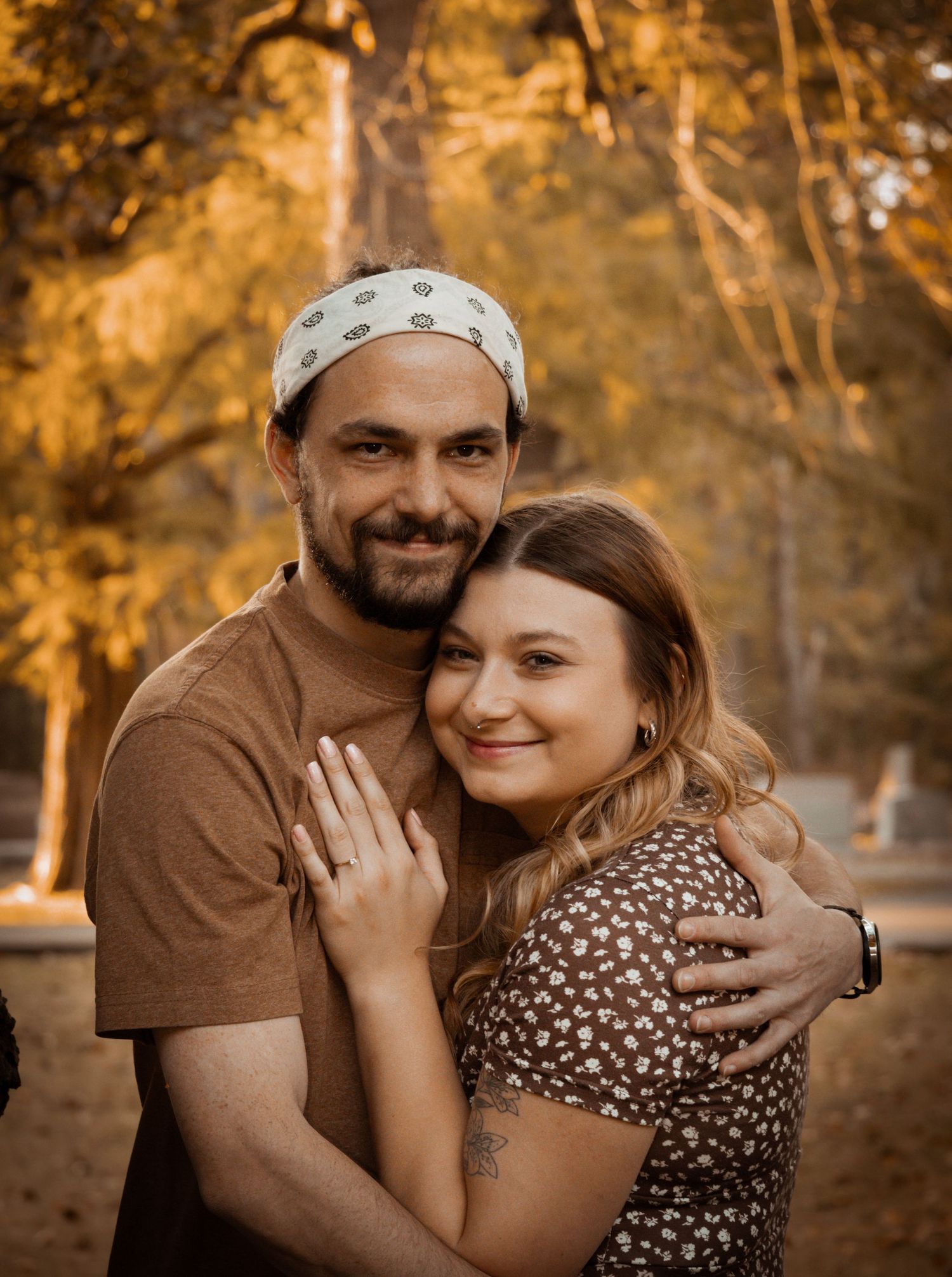 A happily engaged couple's photo in the woods, holding on to each other