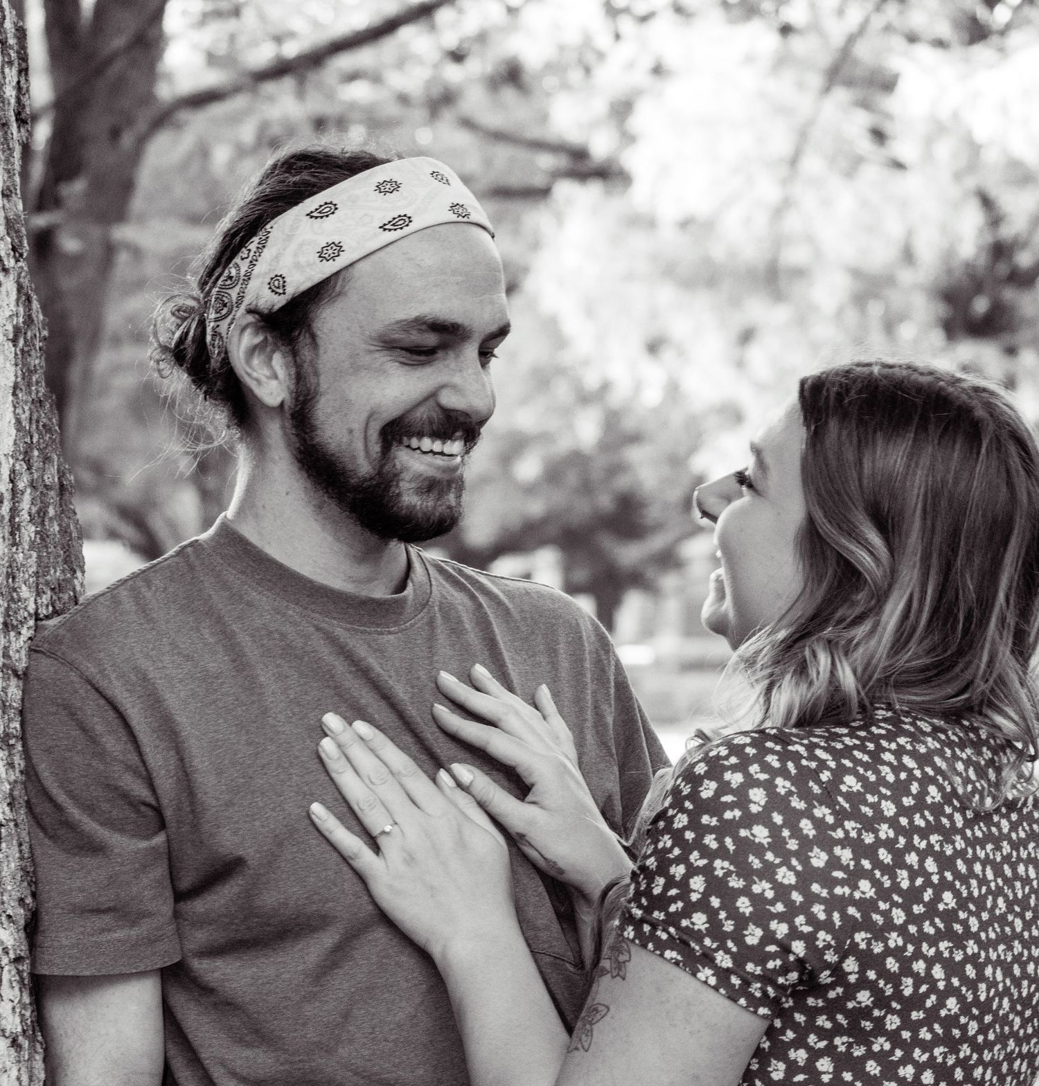 A black and white photo of a happily engaged couple smiling at each other