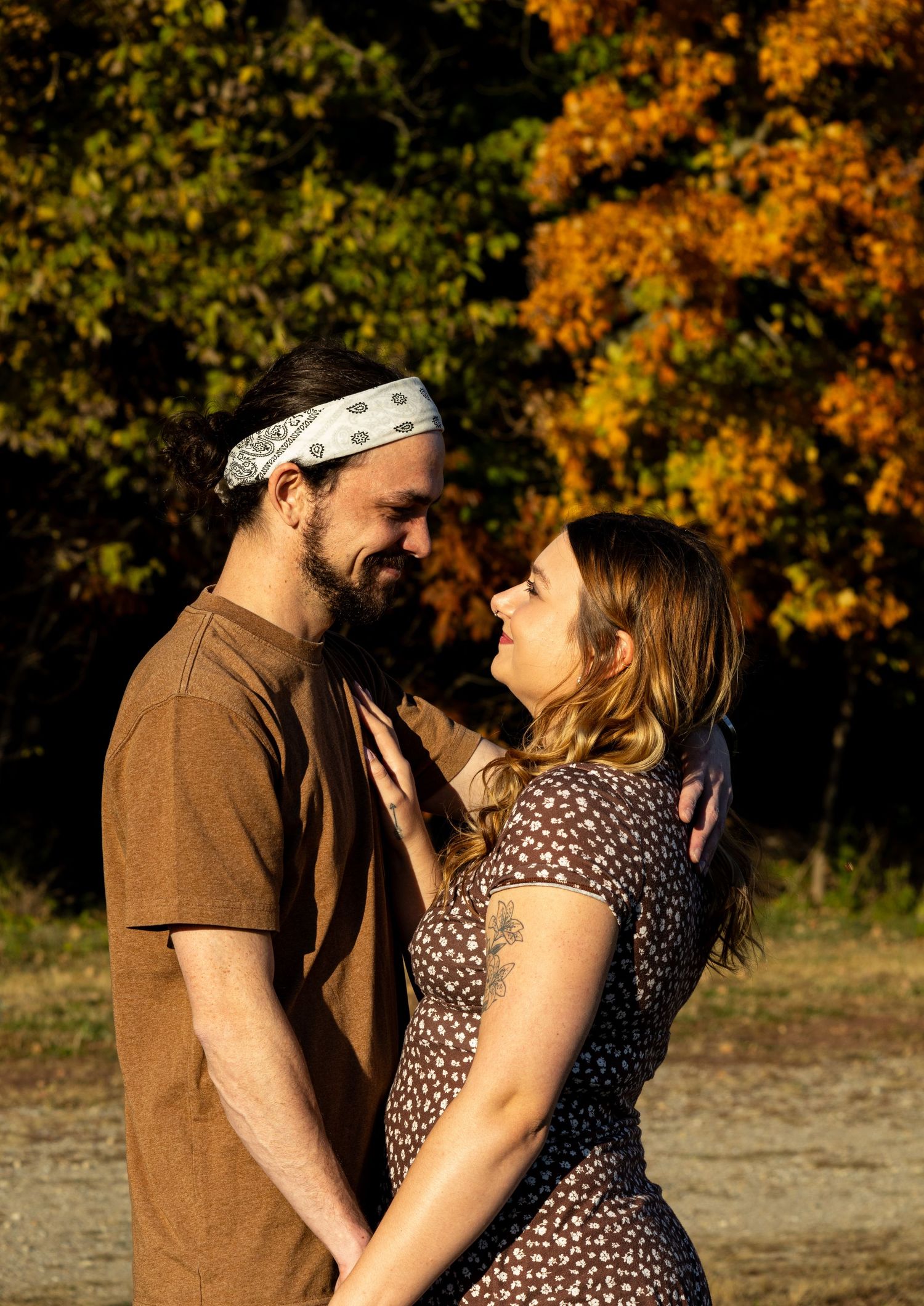 A cozy and happy photo of smiling fiancés holding on to each other as the sun comes through