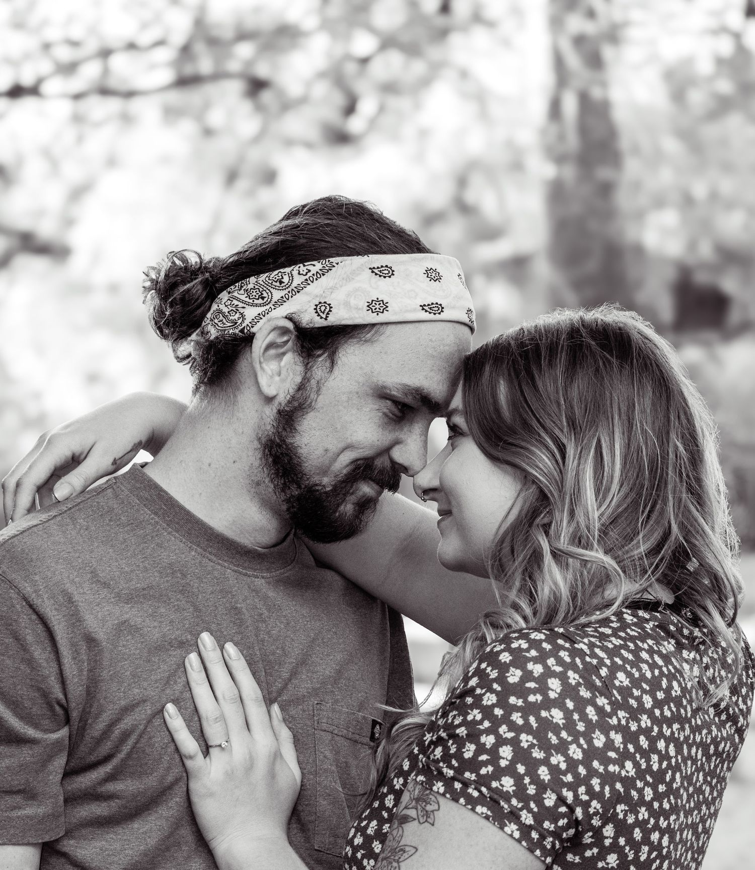 A black and white photo of fiancés (soon to be married) press their foreheads together, and the woman puts her hand on the man's chest