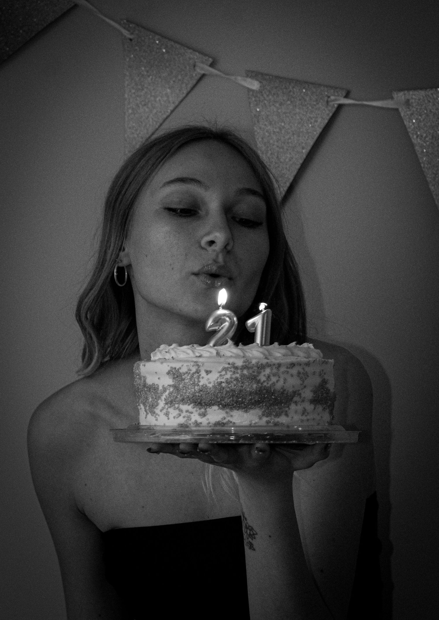 Woman celebrating her twenty-first birthday by blowing out the candles on her cake