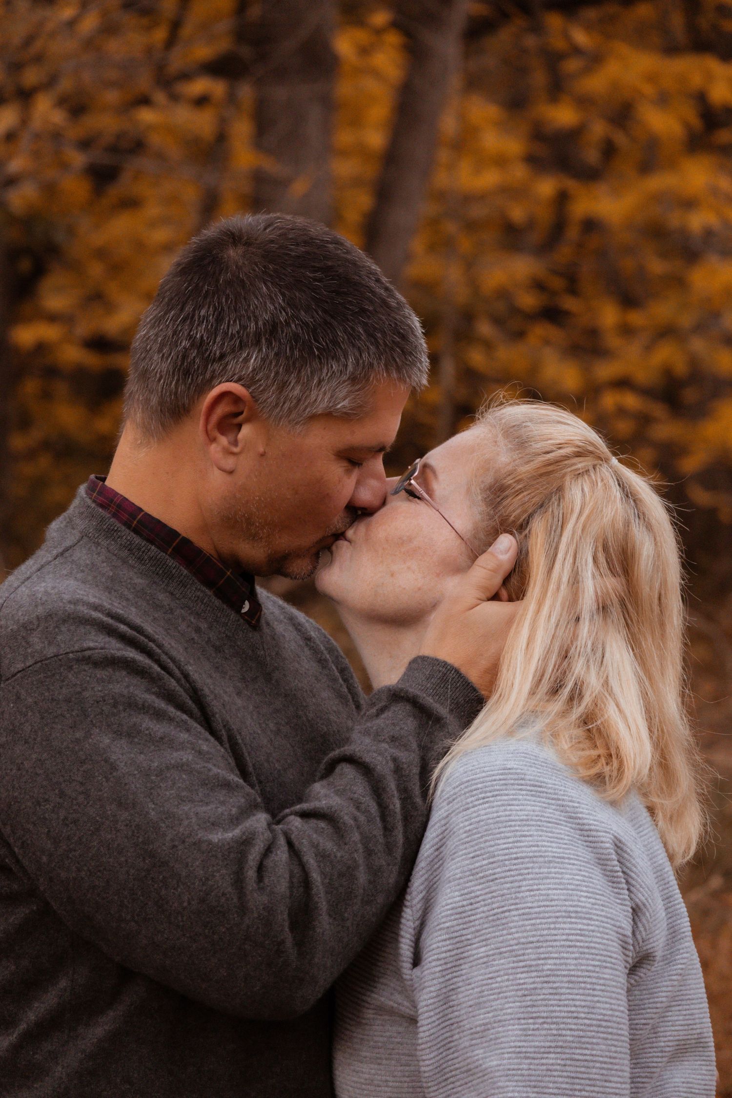 A happily married couple kissing each other in the woods