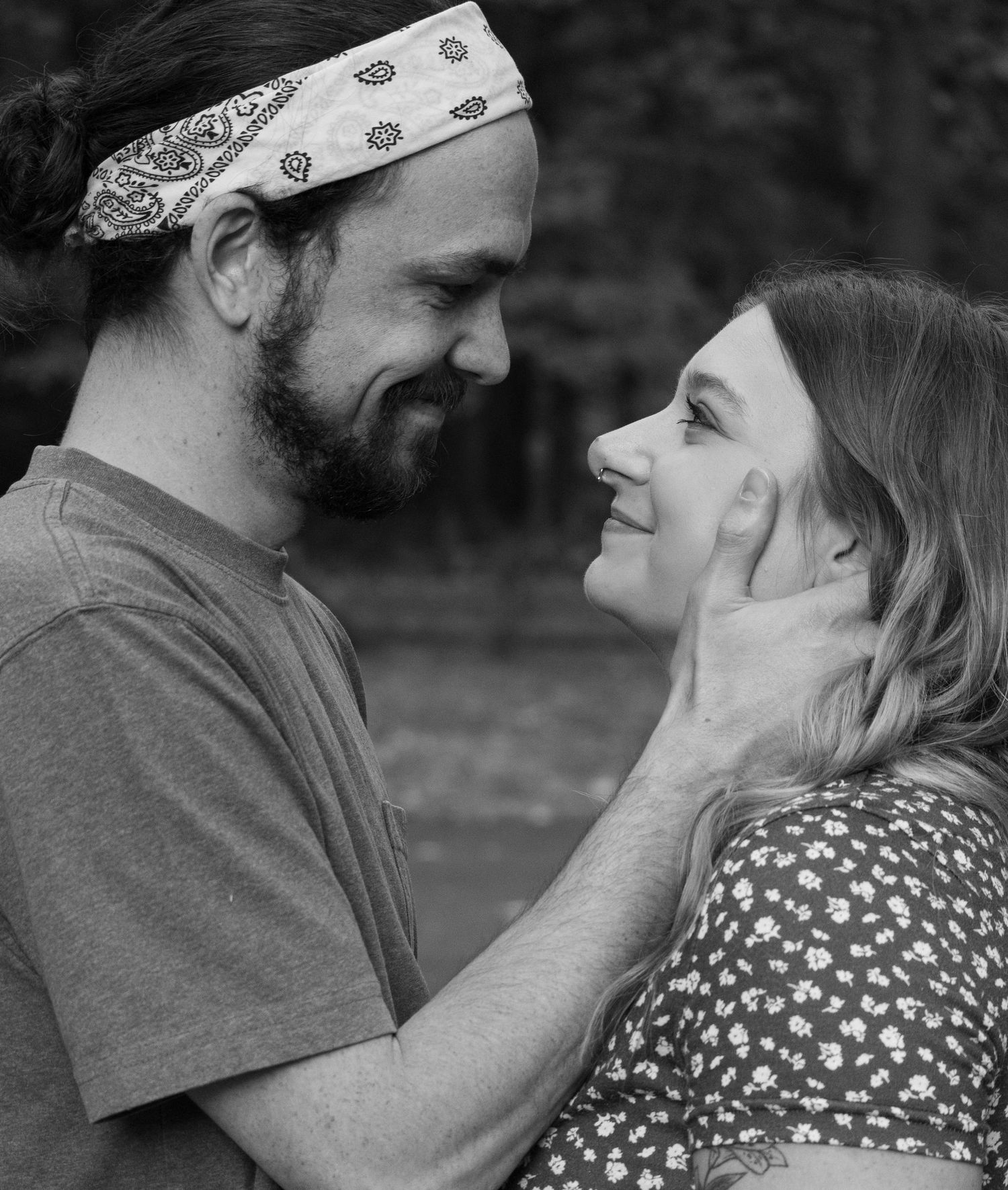 A black and white photo of an engaged couple staring into each other's eyes. The man is holding the woman's face tenderly.