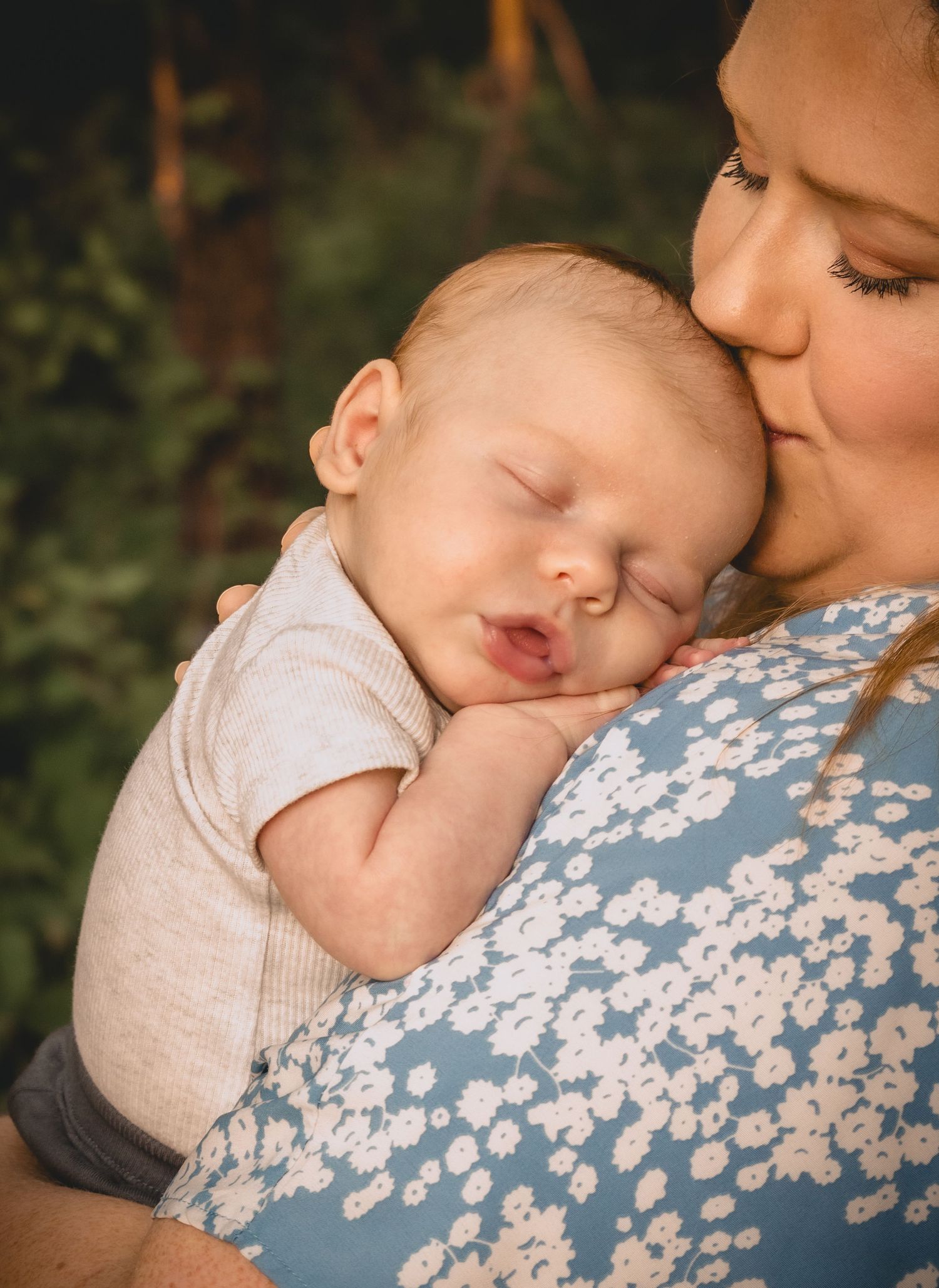 A mom holding her sleeping newborn against her chest.