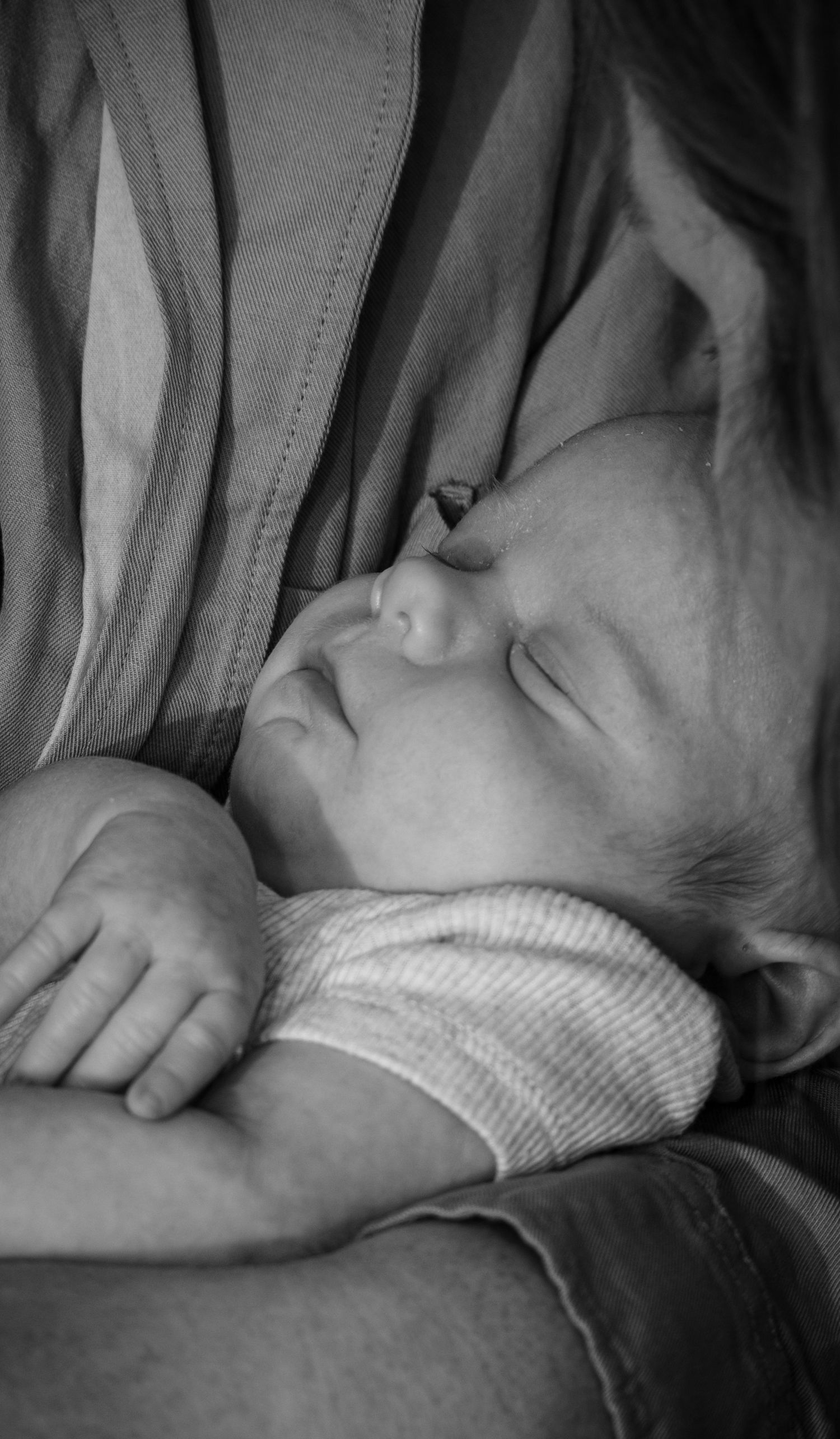 A black and white photo of a sleeping newborn being held
